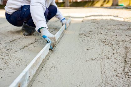 Professional contractor leveling fresh wet concrete on a job site.