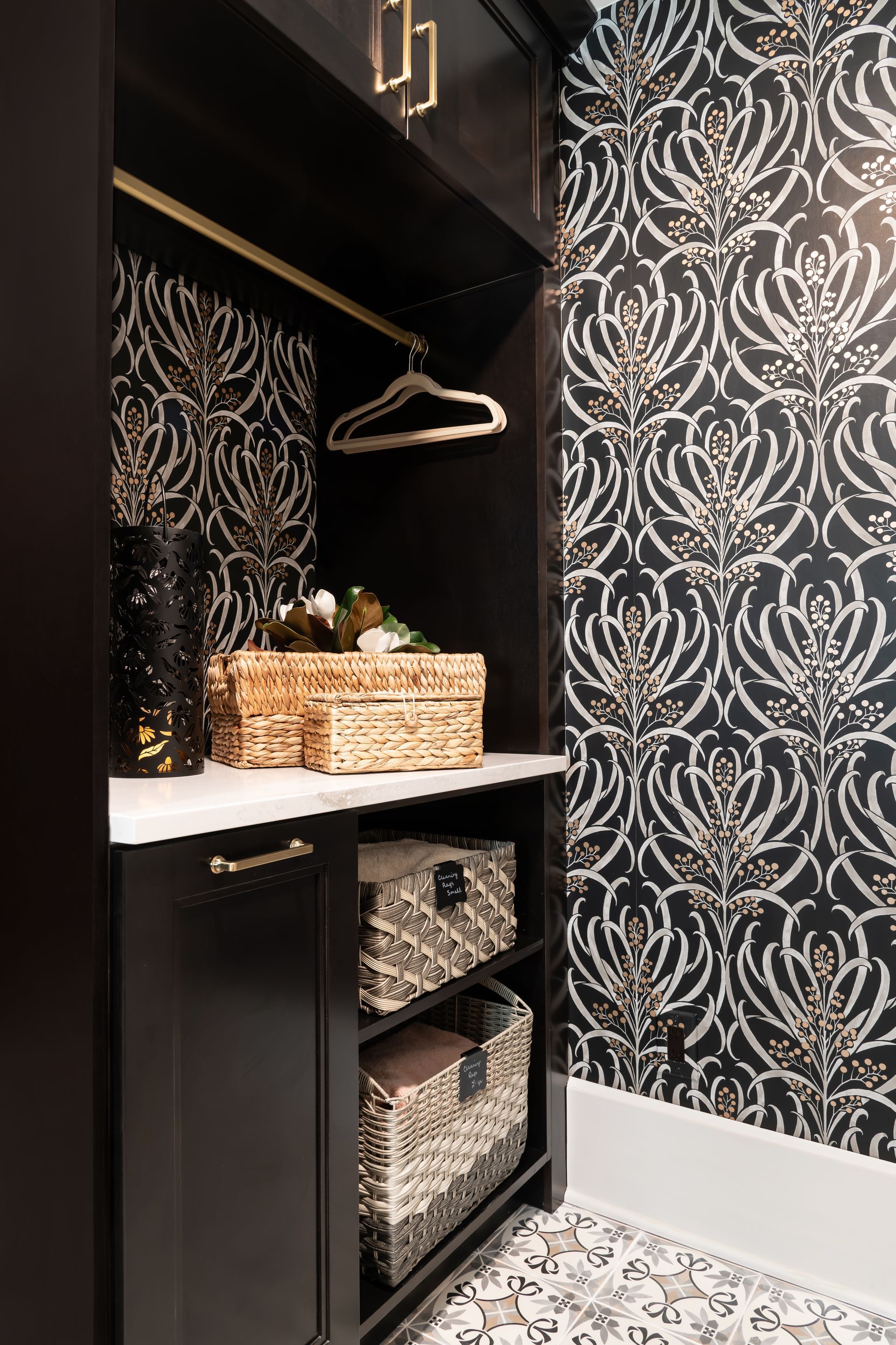 A laundry room with black and white wallpaper and baskets on shelves.