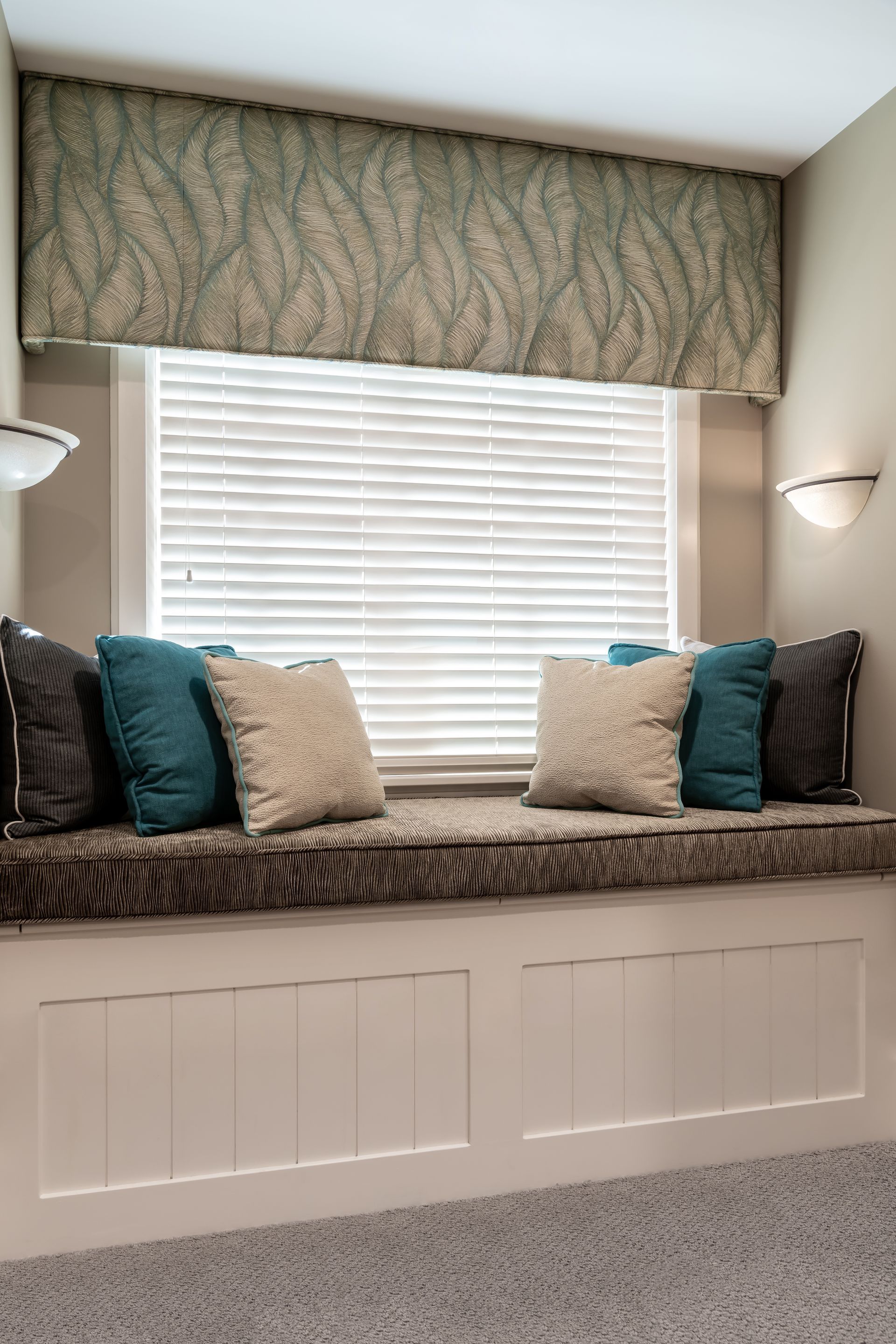 A window seat with blue and white pillows in front of a window.