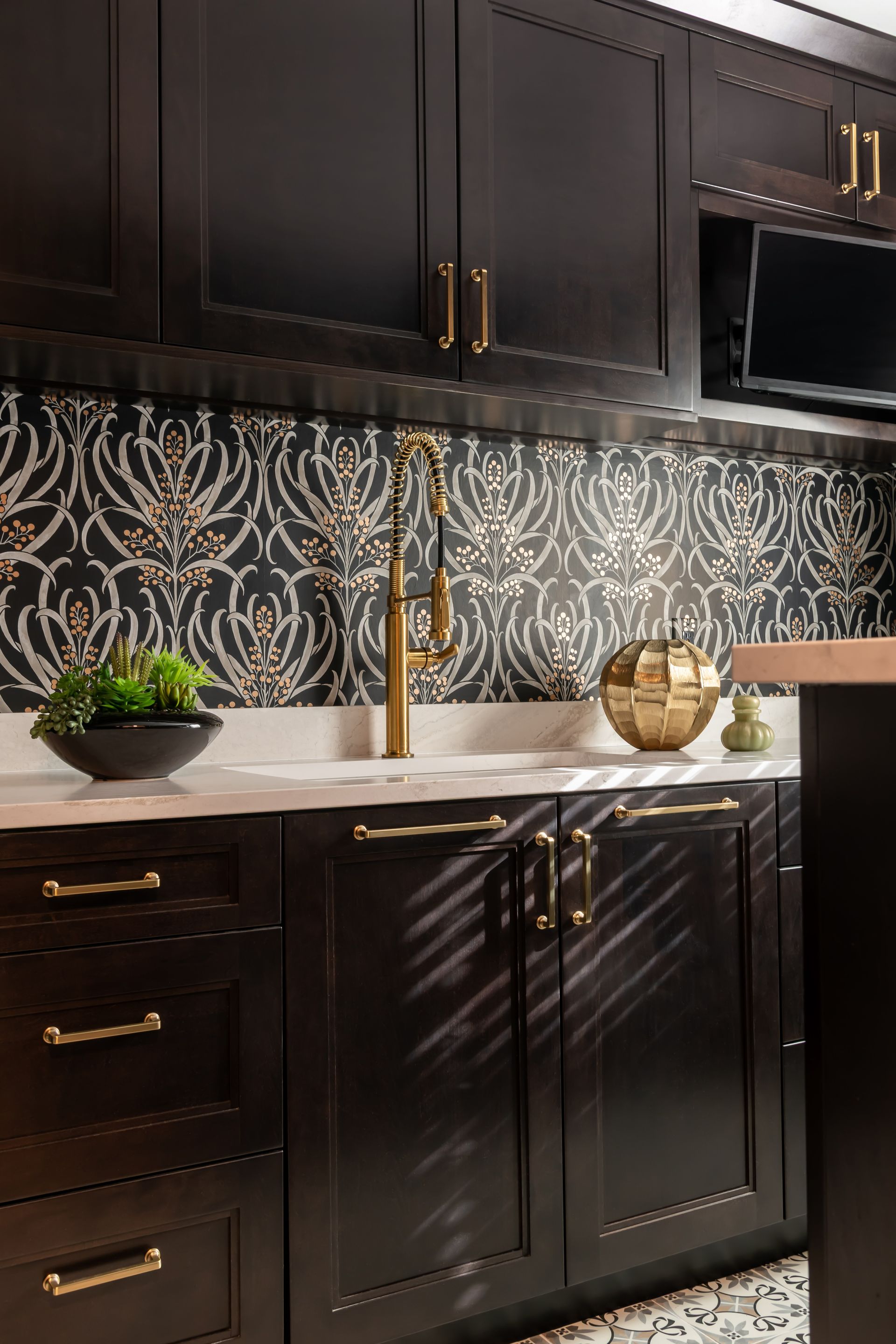 A kitchen with black cabinets , a sink , and a microwave.
