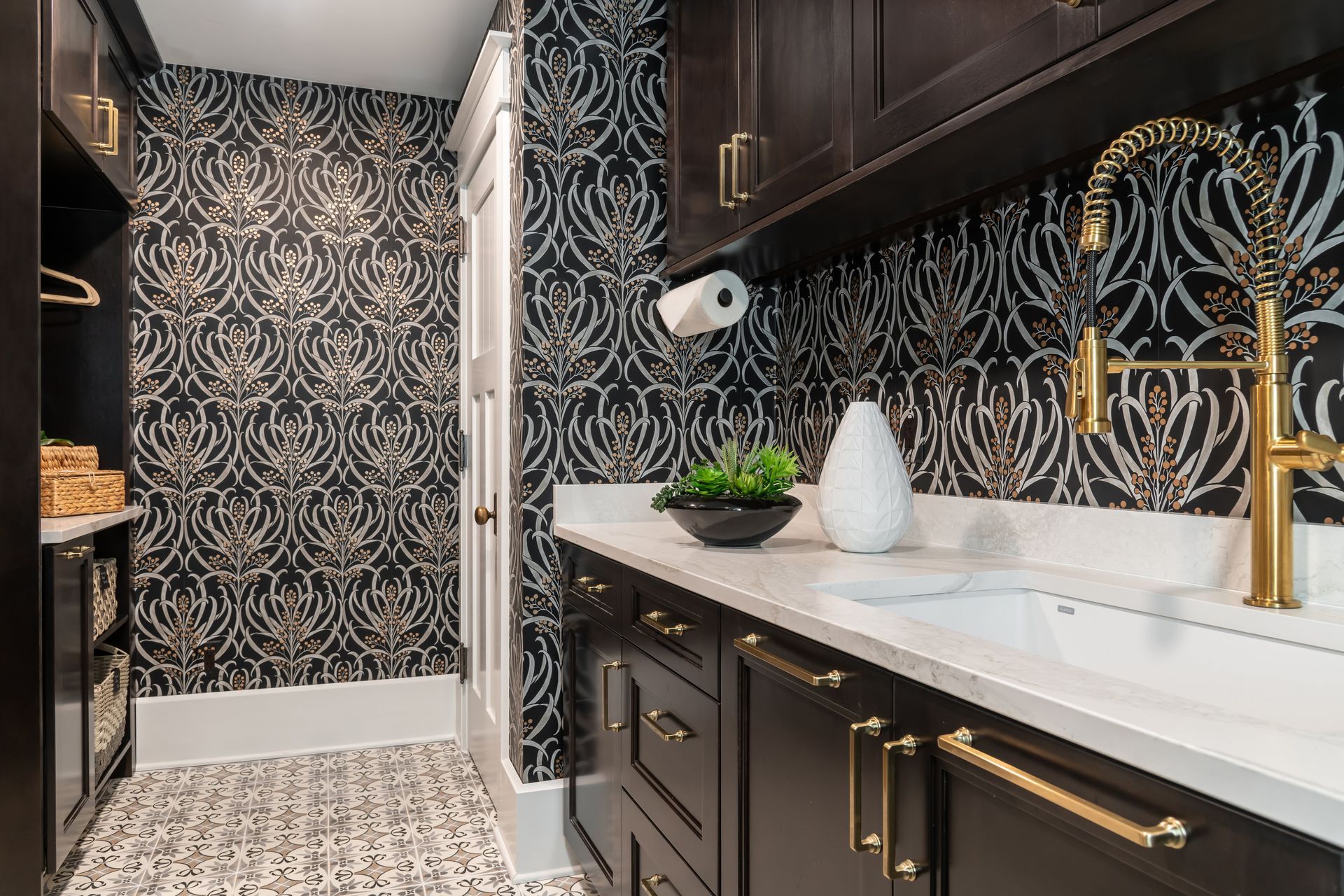 A laundry room with black and gold wallpaper and a sink.