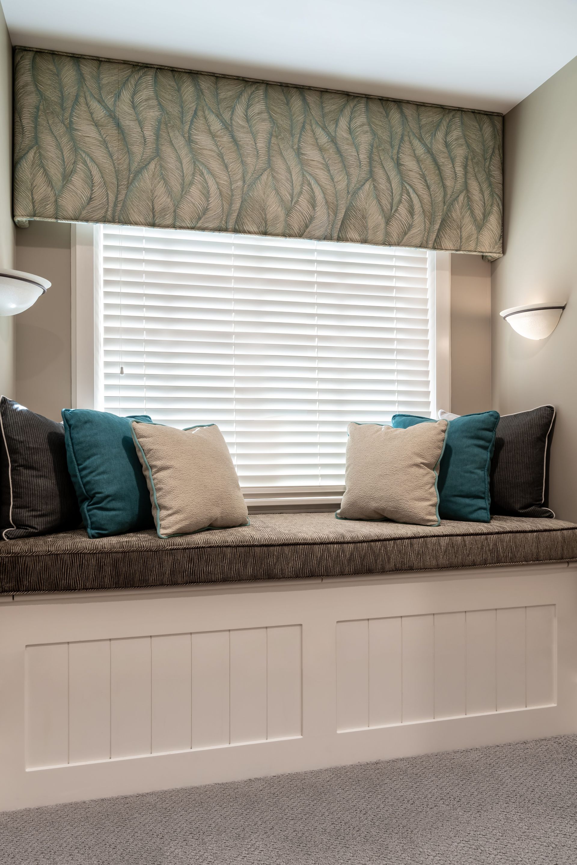 A window seat with blue and white pillows in front of a window.