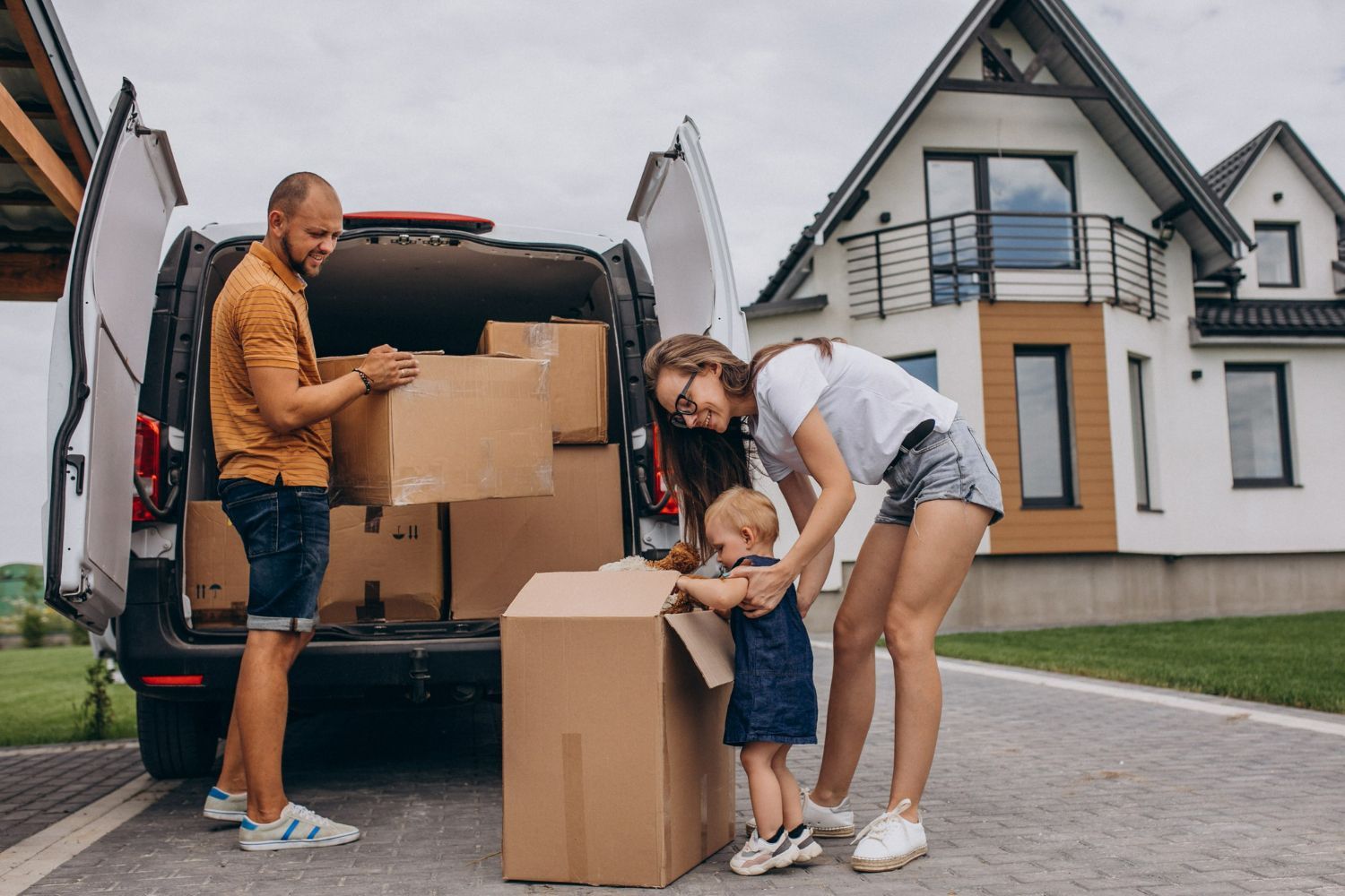 A family is loading boxes into a van in front of a house.