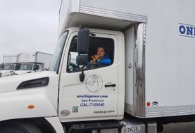 a man with a dog in the driver 's seat of a one big man truck