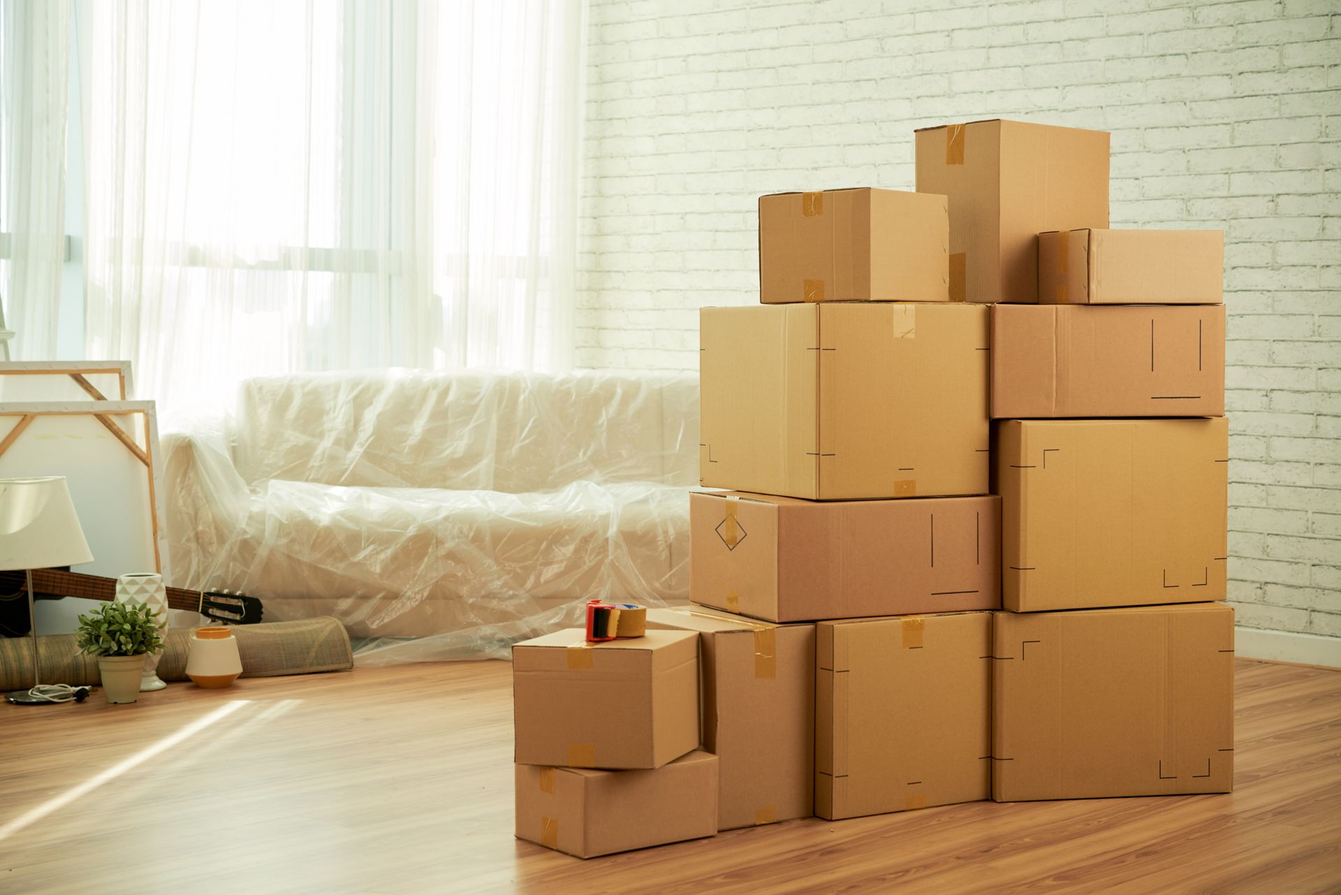 Boxes stacked in a room with a covered couch, indicating a move or packing.