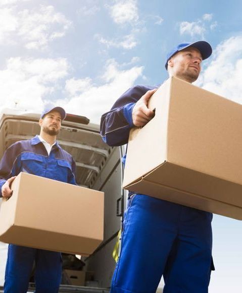 Two men are carrying boxes out of a van.