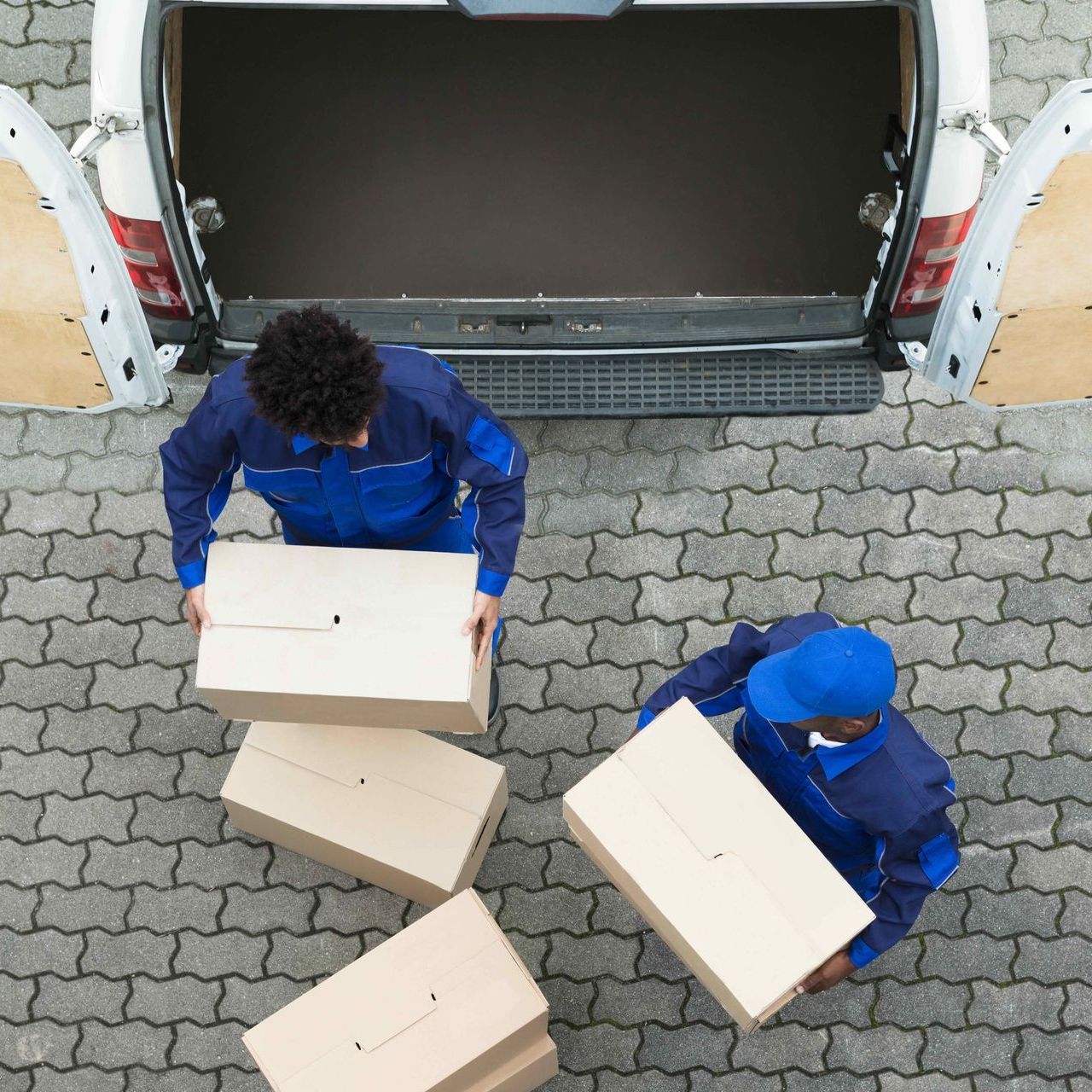 Two delivery men are loading boxes into the back of a van.