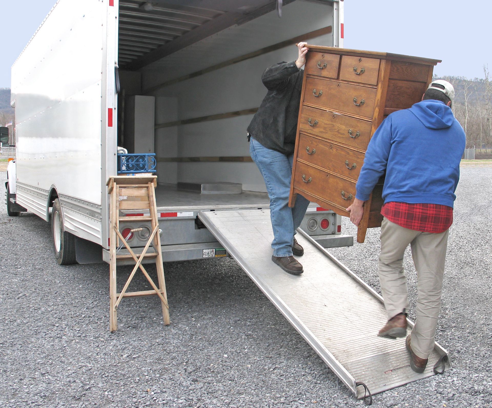 Two men are loading a dresser into a truck