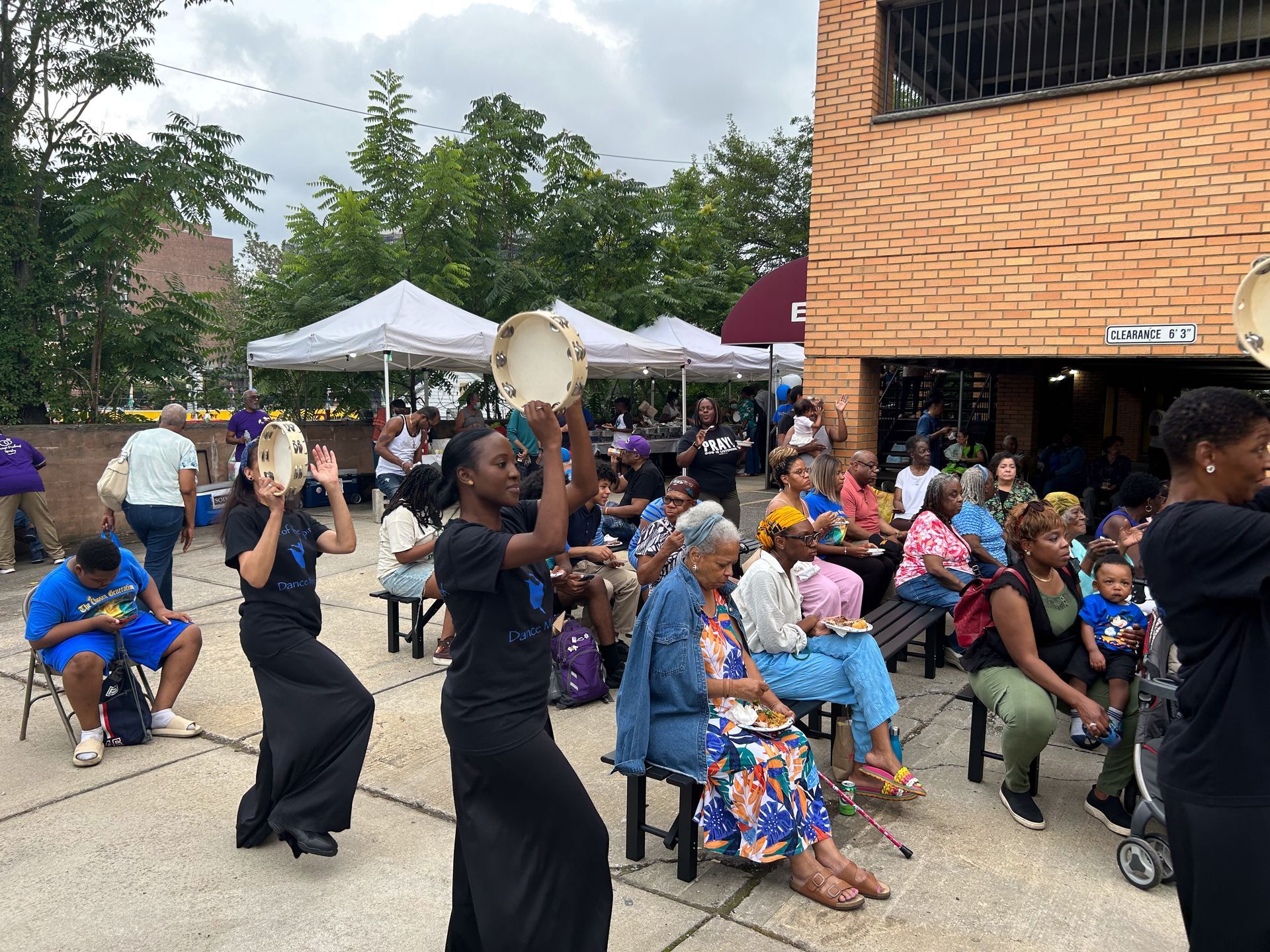 A group of people are dancing in front of a brick building.