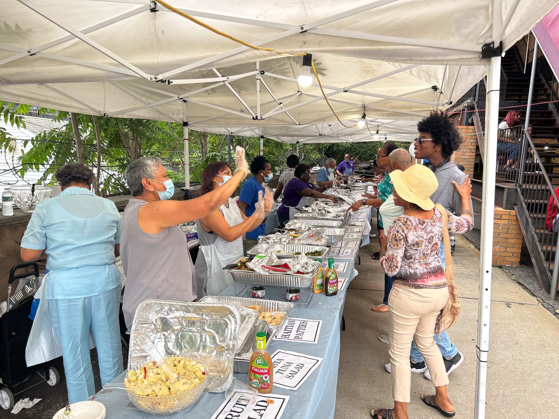 A group of people are standing around a buffet table under a tent.