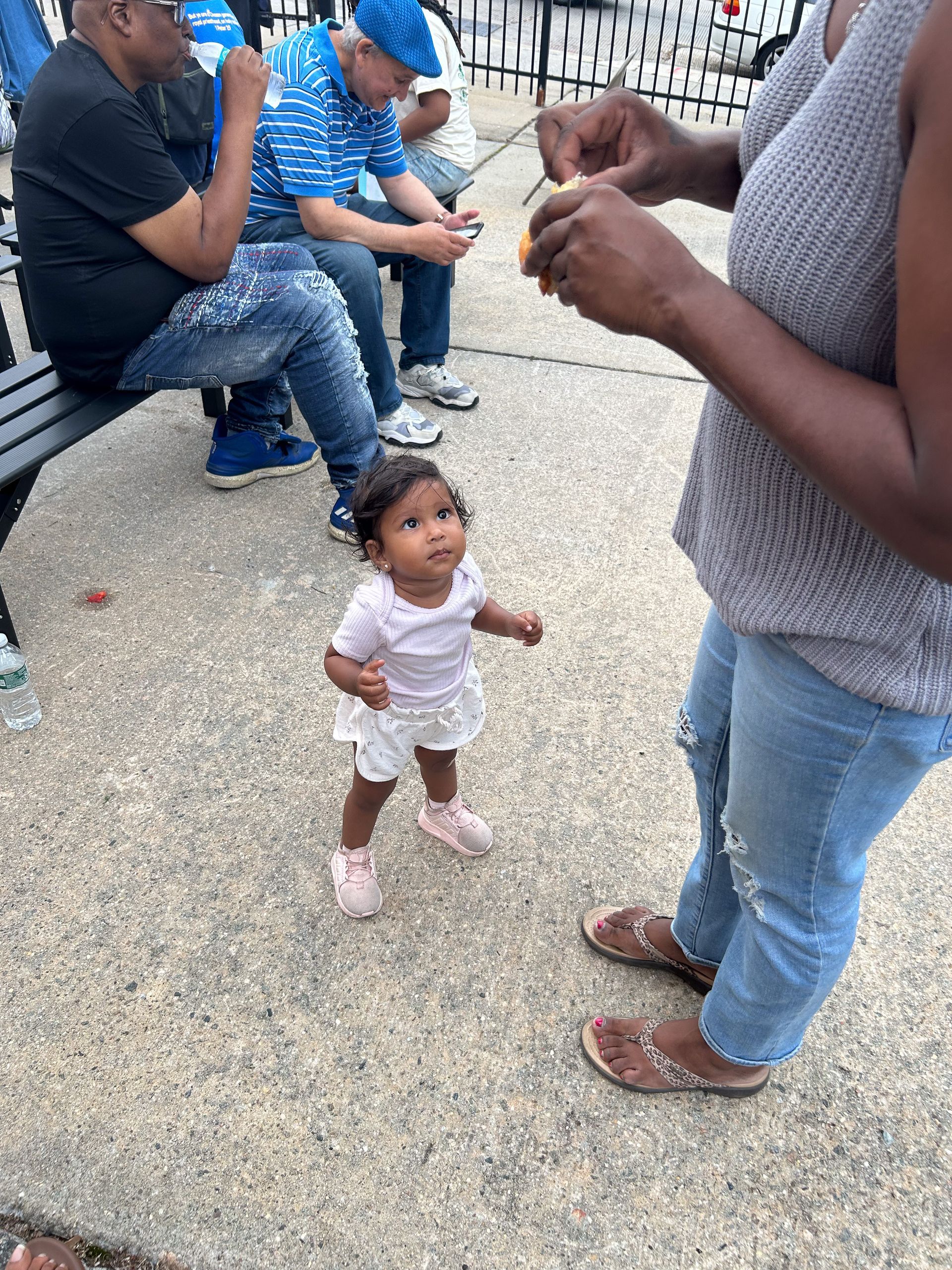 A little girl is standing next to a woman on a sidewalk.