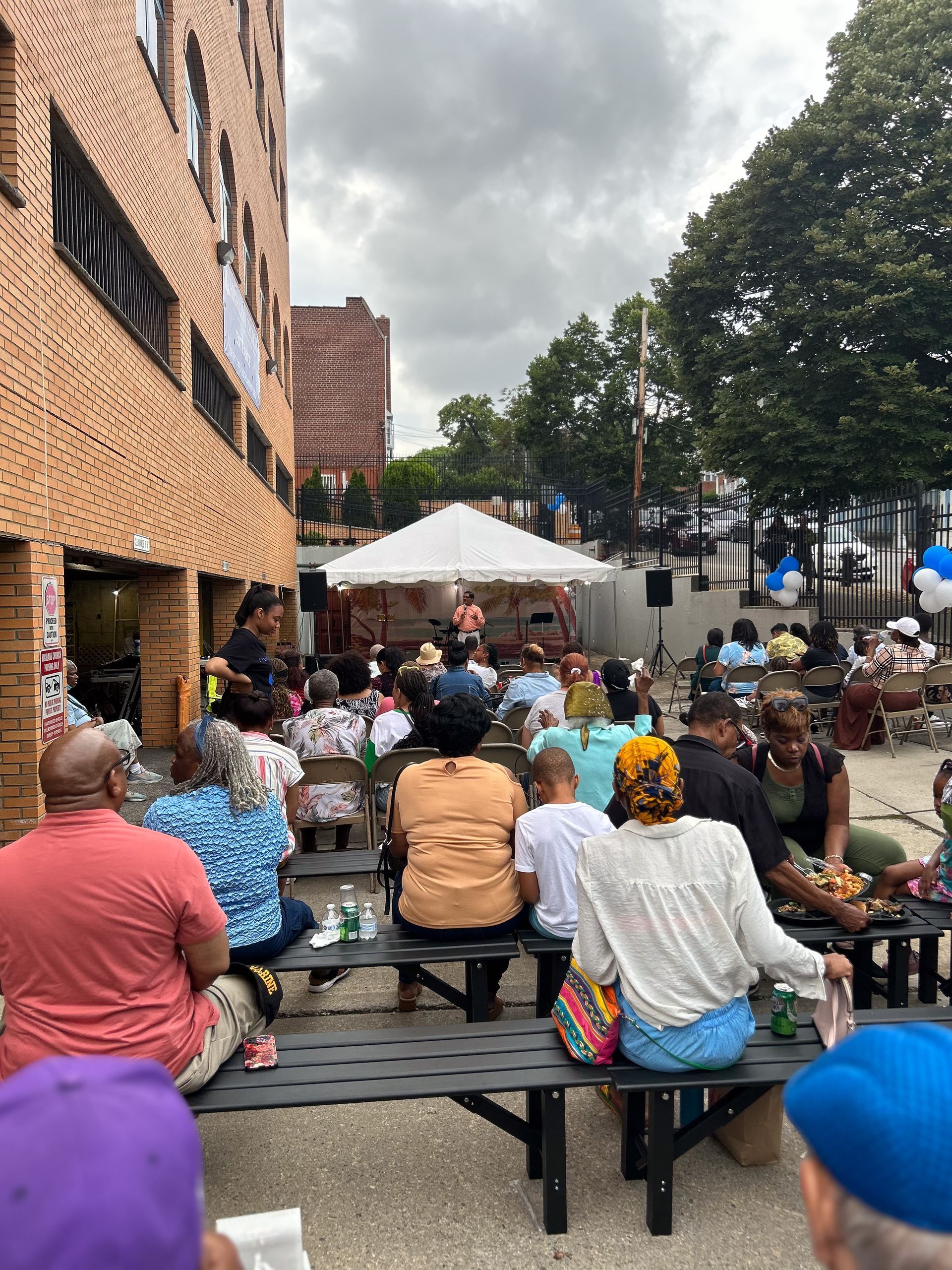 A group of people are sitting on benches watching a concert.