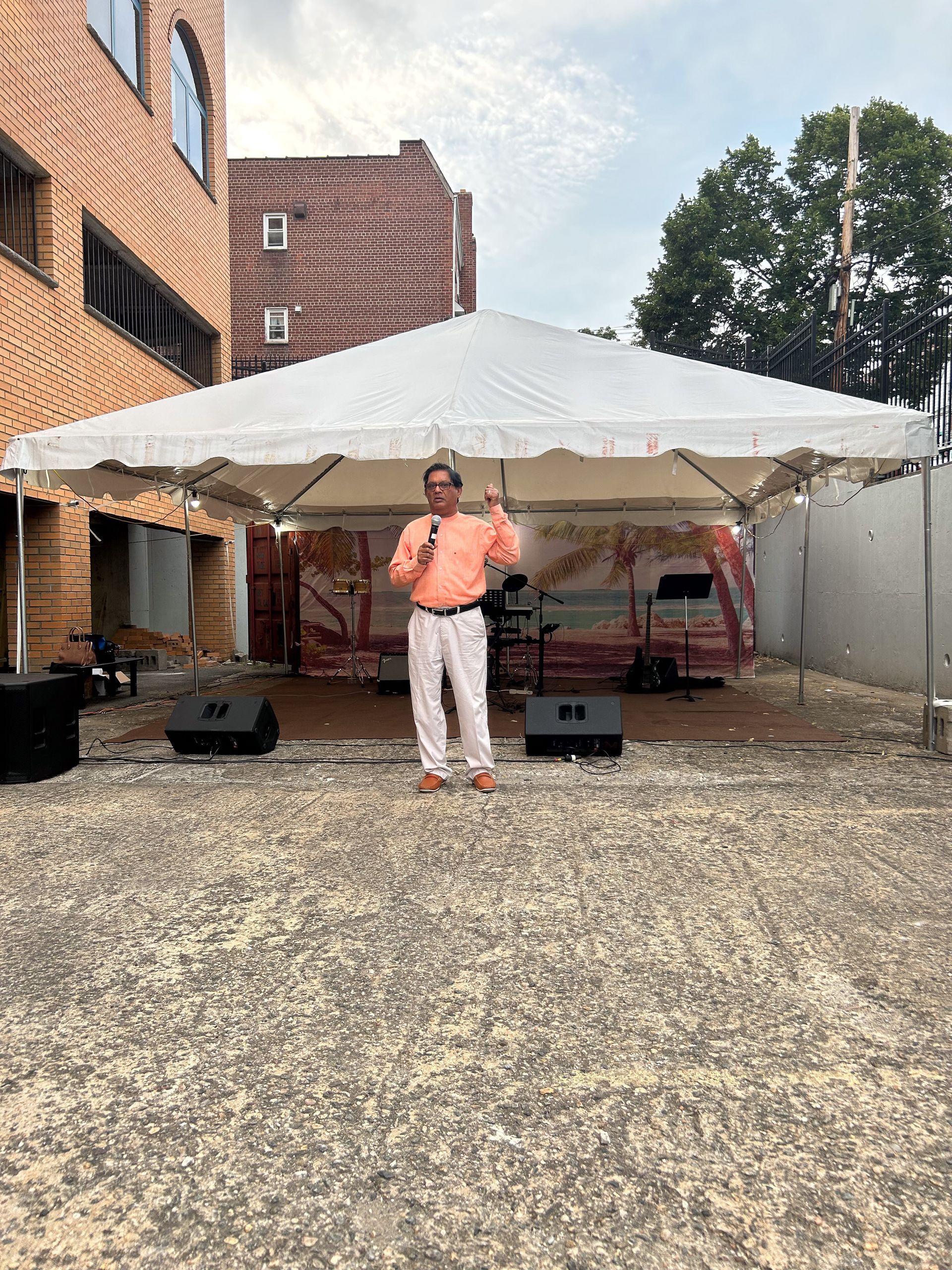 A man is standing in front of a white tent holding a microphone.