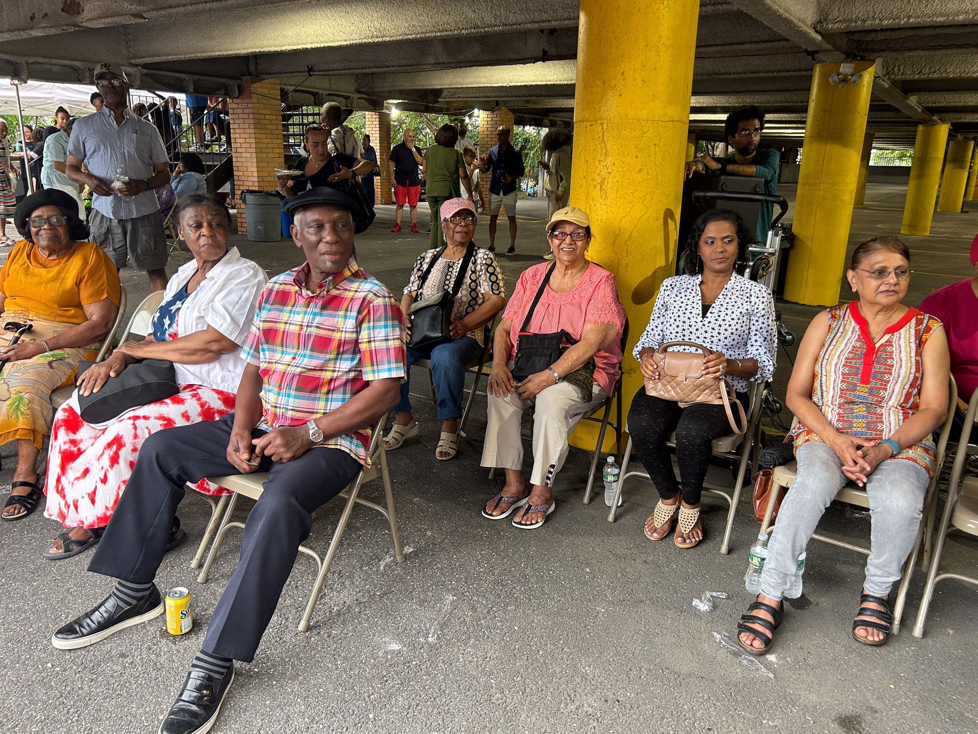 A group of people are sitting in chairs under a bridge.
