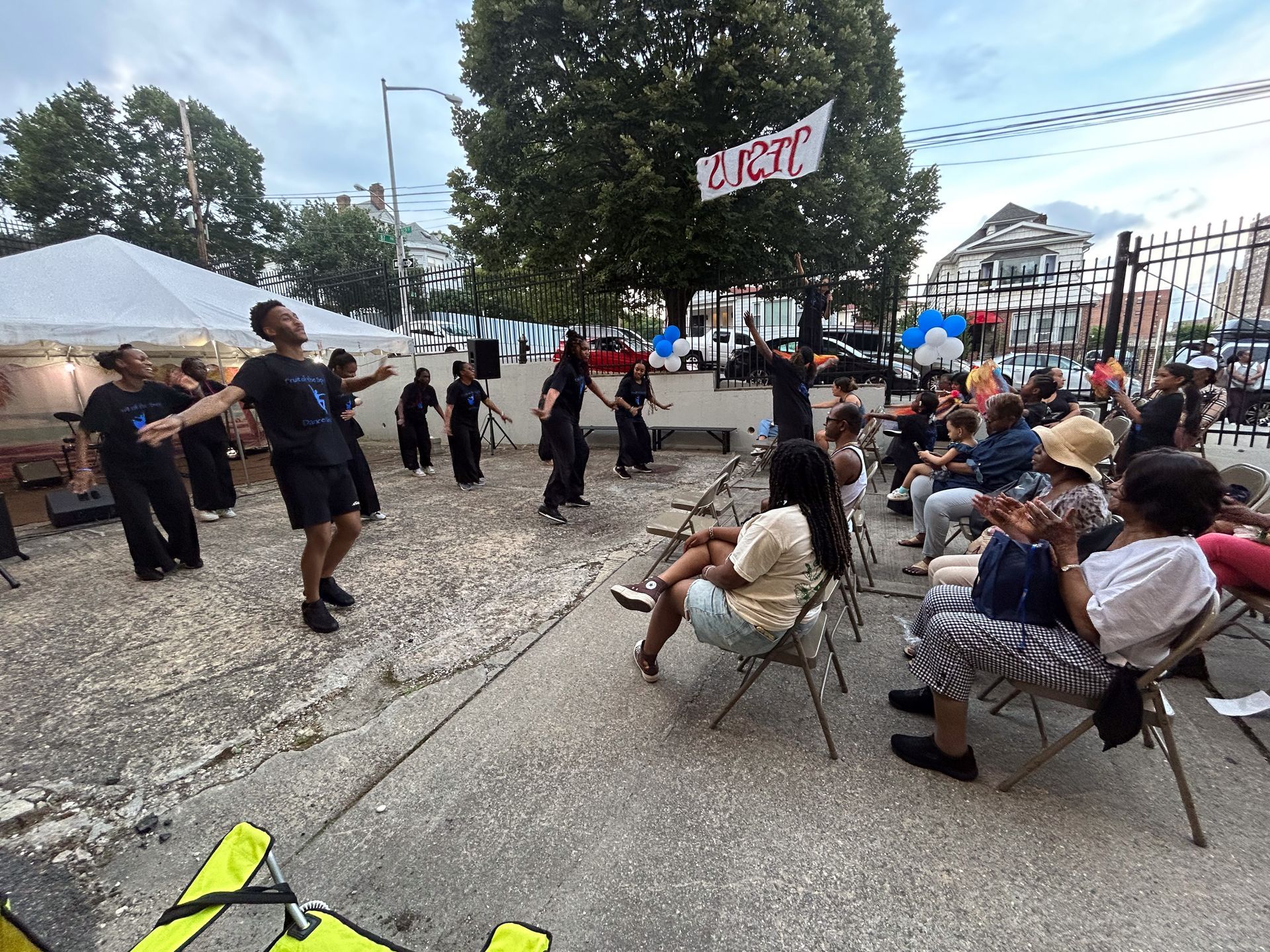 A group of people are sitting in chairs and dancing in a park.