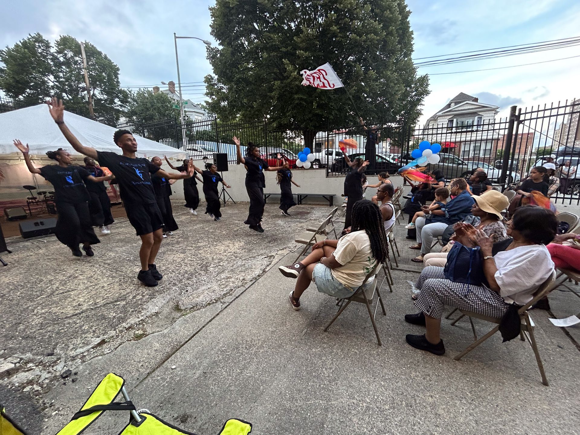 A group of people are sitting in chairs watching a group of people perform a dance.