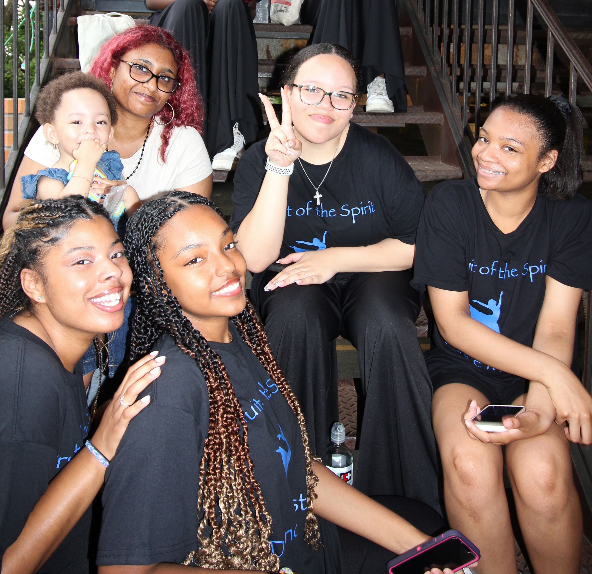 A group of women are posing for a picture and one of them is wearing a shirt that says 