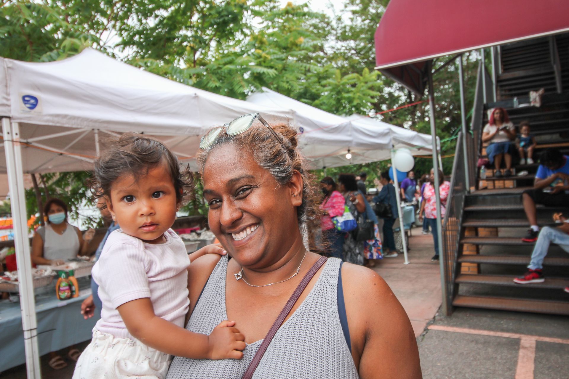 A woman is holding a baby in her arms at a market.