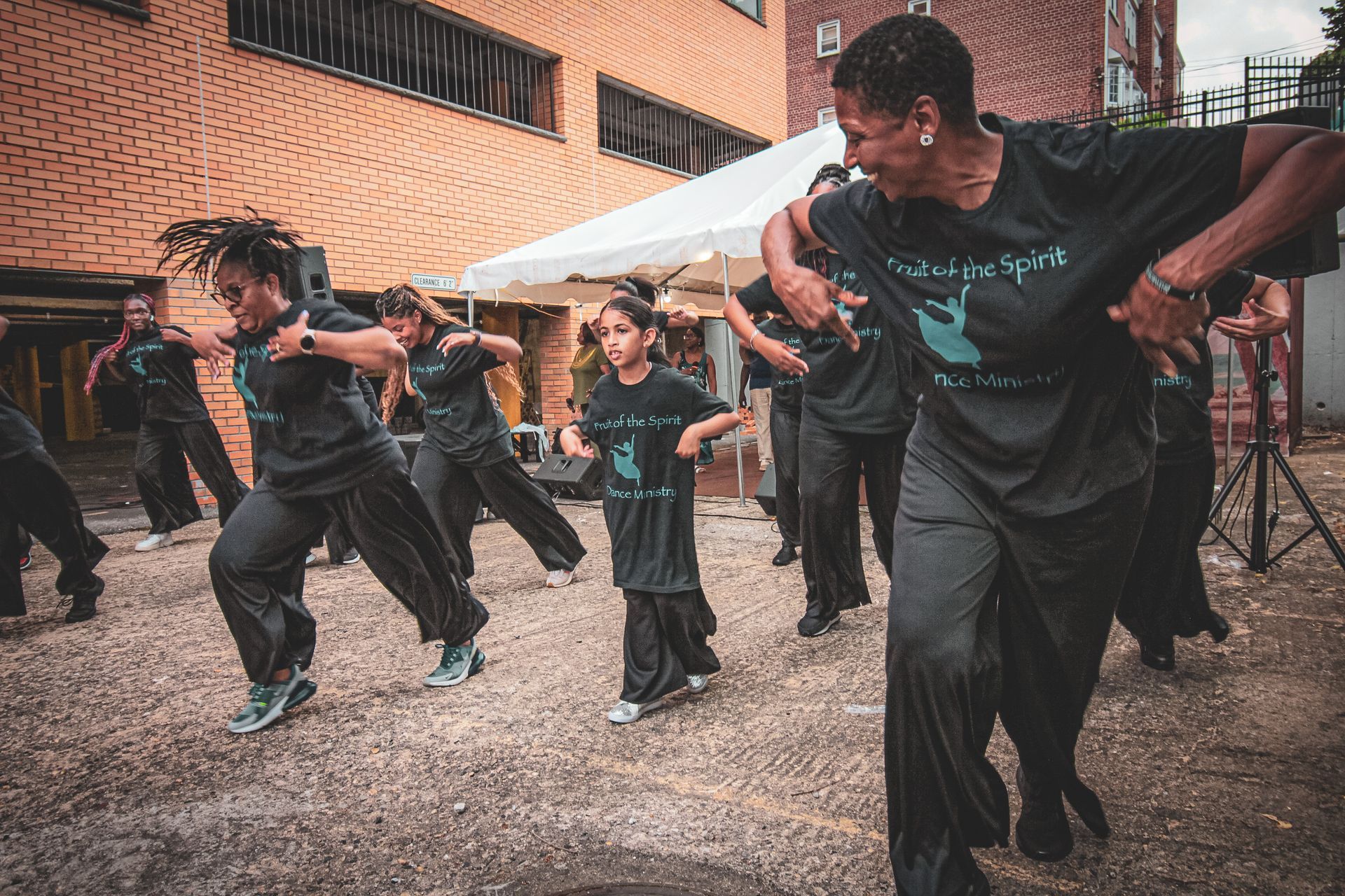 A group of people are dancing in front of a brick building.