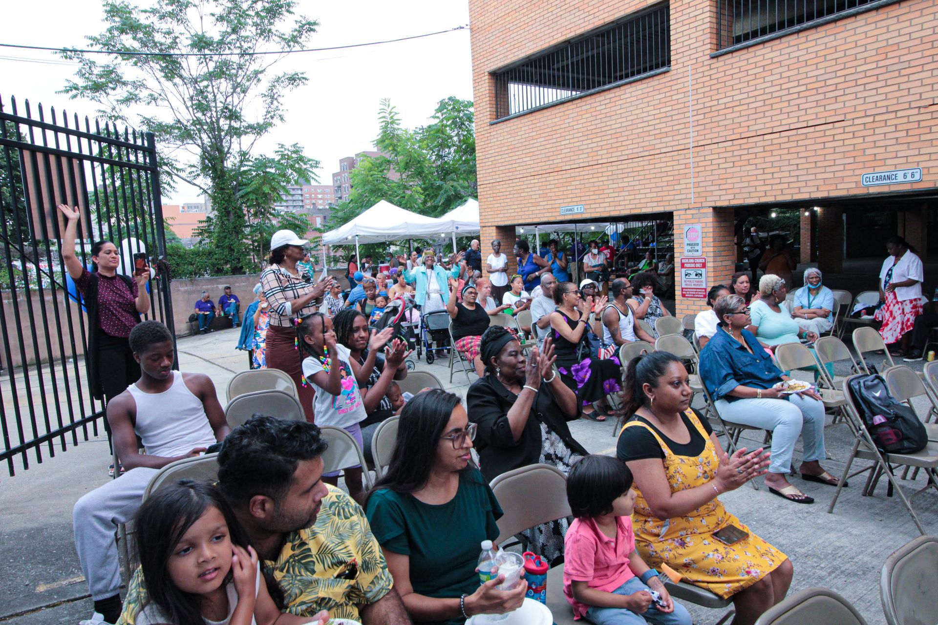 A large group of people are sitting in chairs outside of a building.