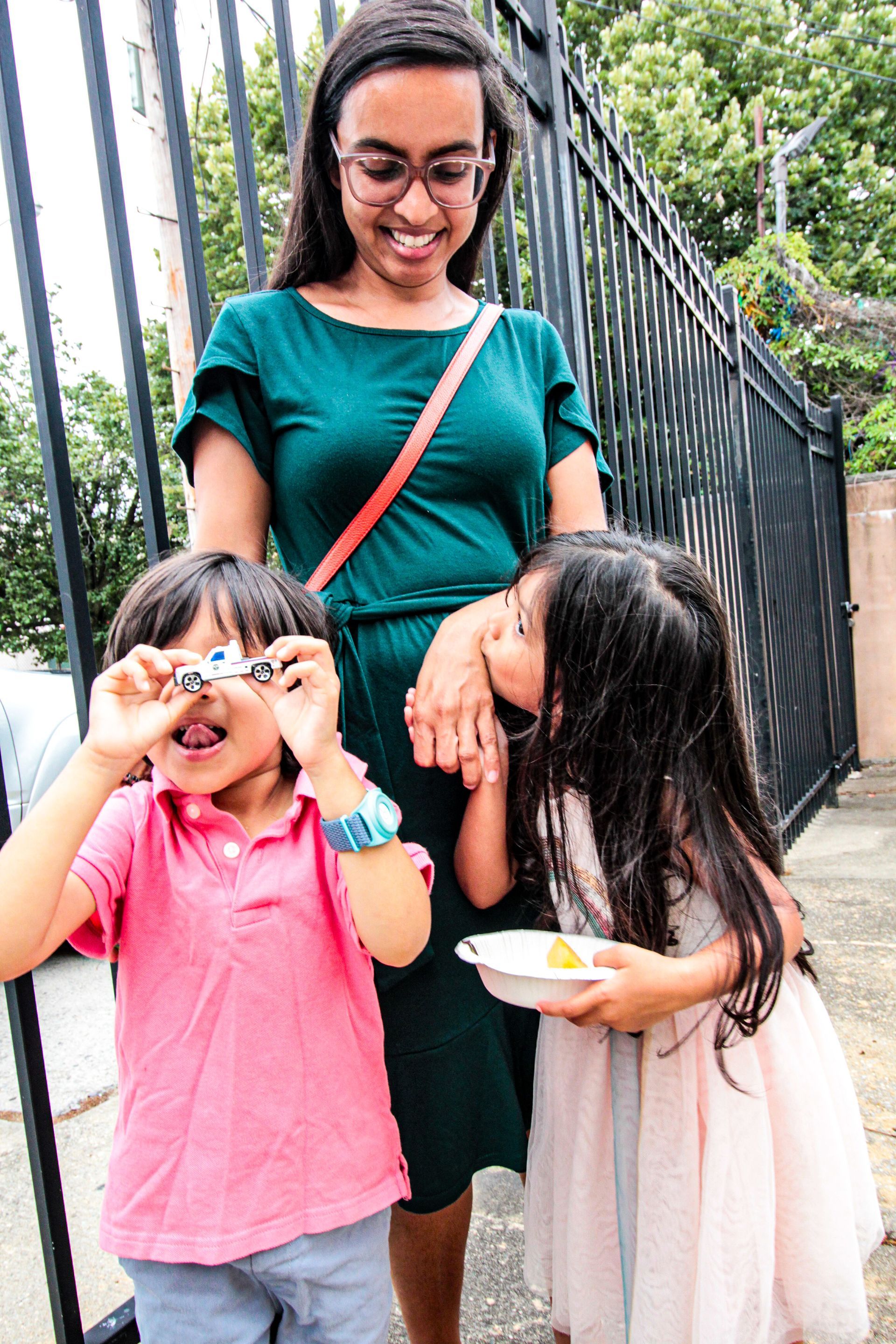 A woman is standing next to two children looking through binoculars.
