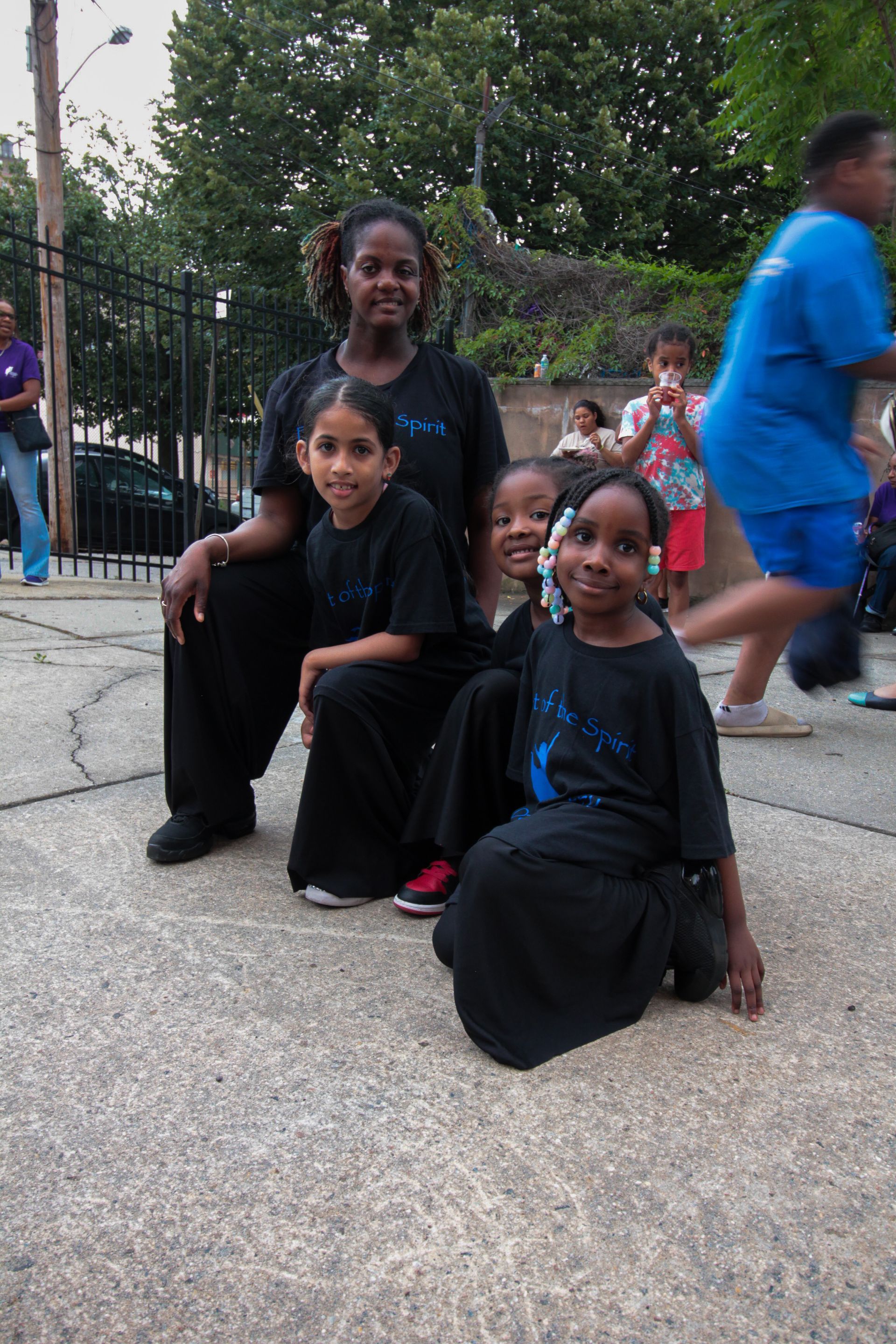 A group of children are posing for a picture on the sidewalk.