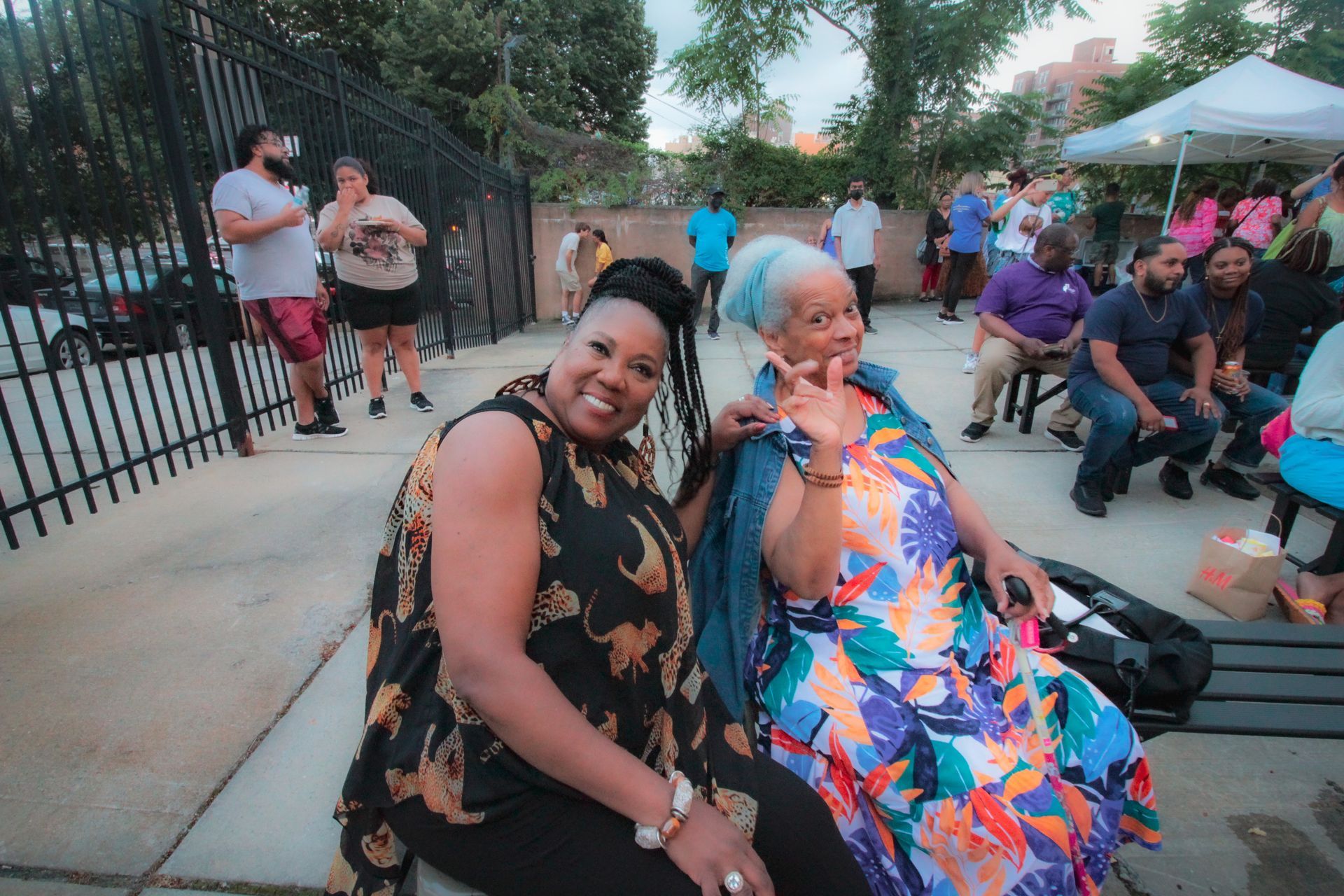 Two women are posing for a picture while sitting on a bench.