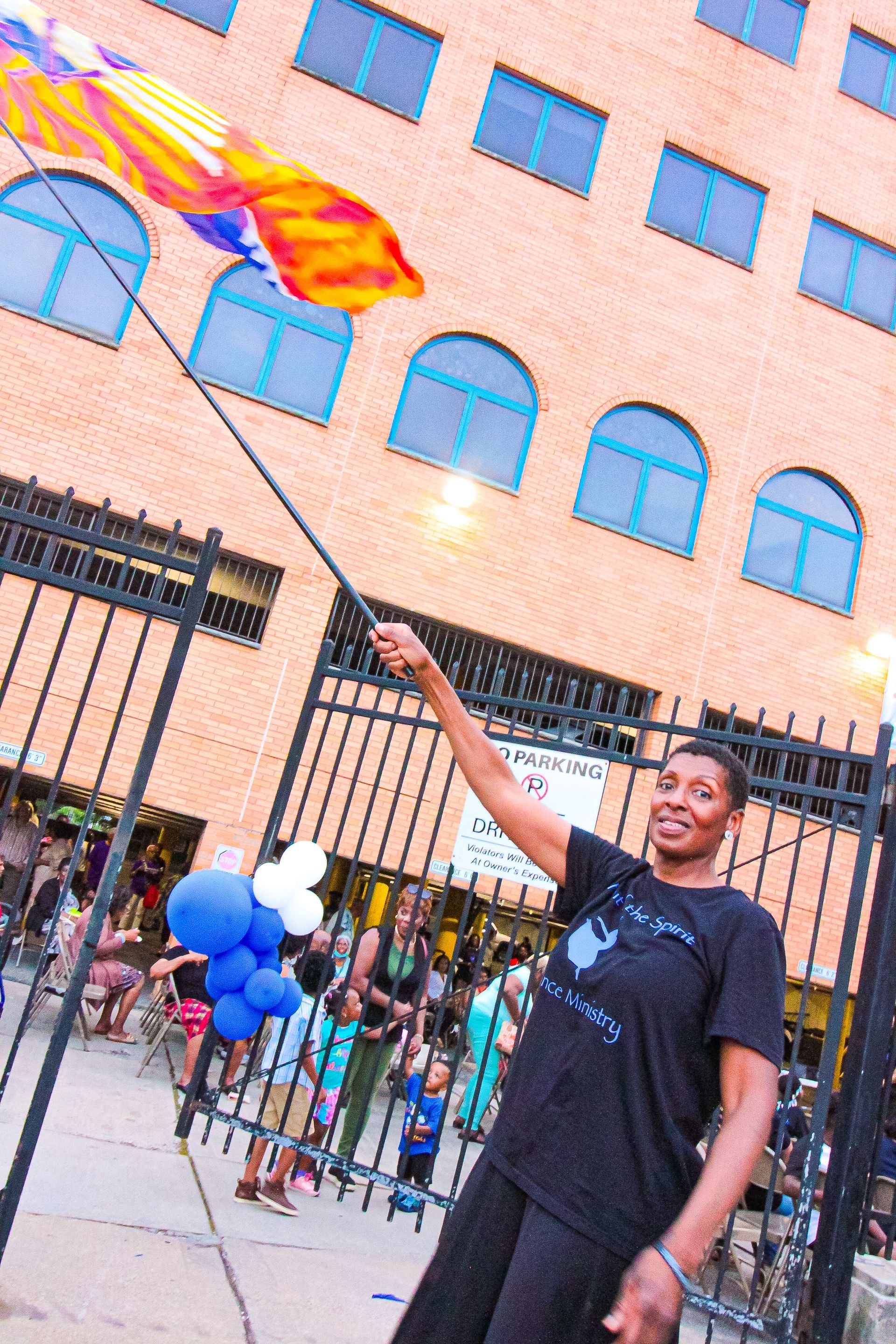 A woman is holding a flag in front of a building
