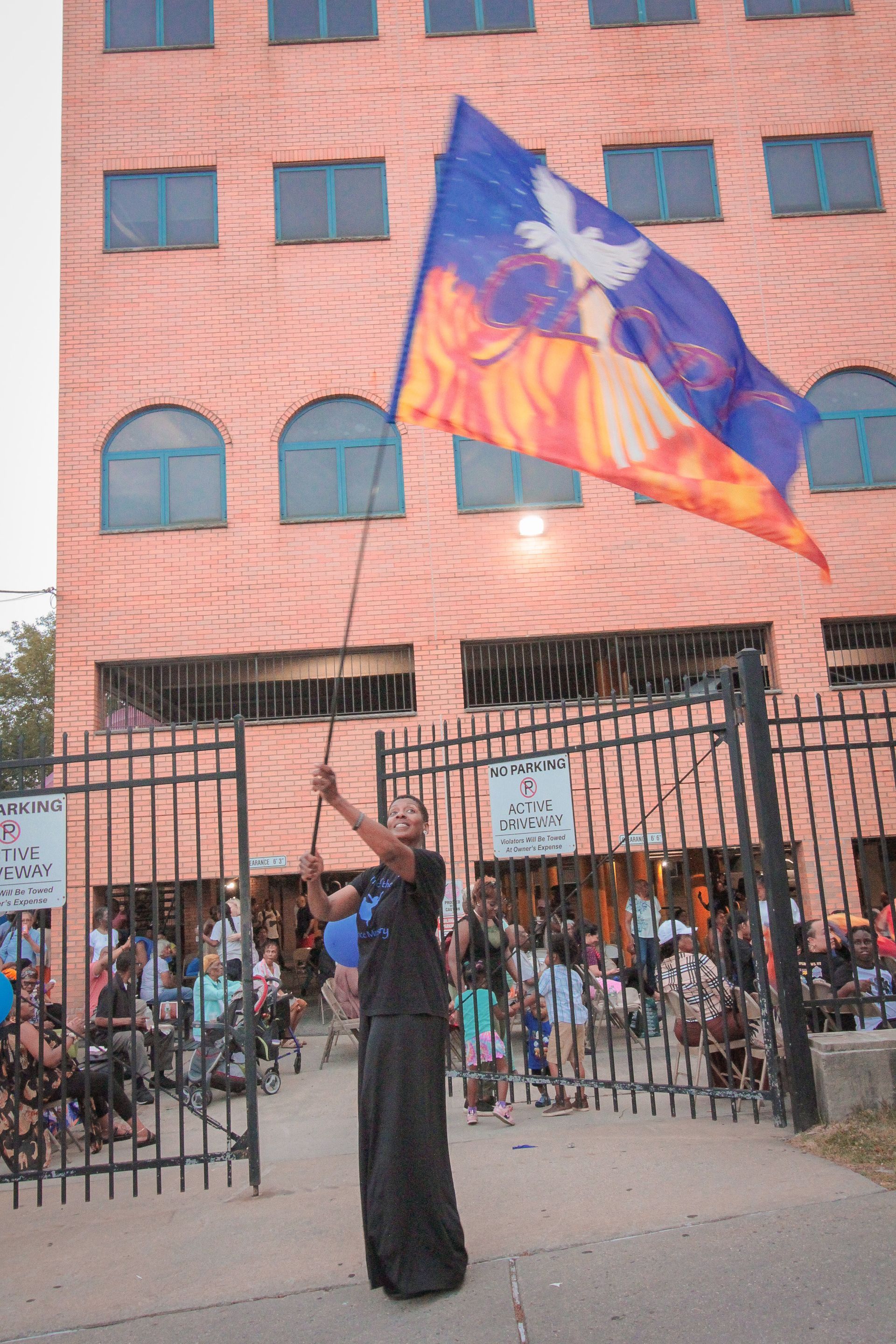 A person on stilts holding a flag in front of a building