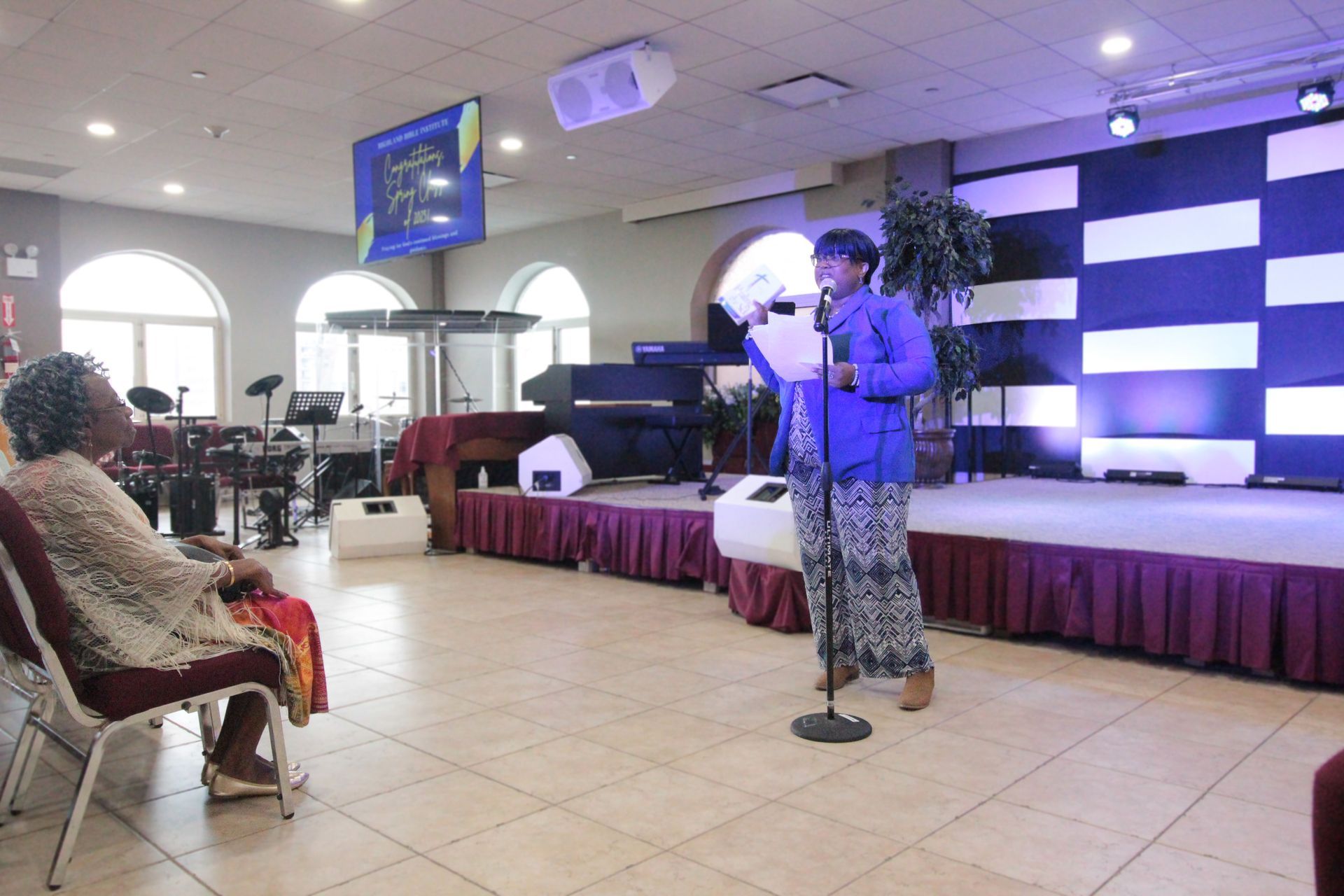 A woman is standing in front of a microphone in a room.