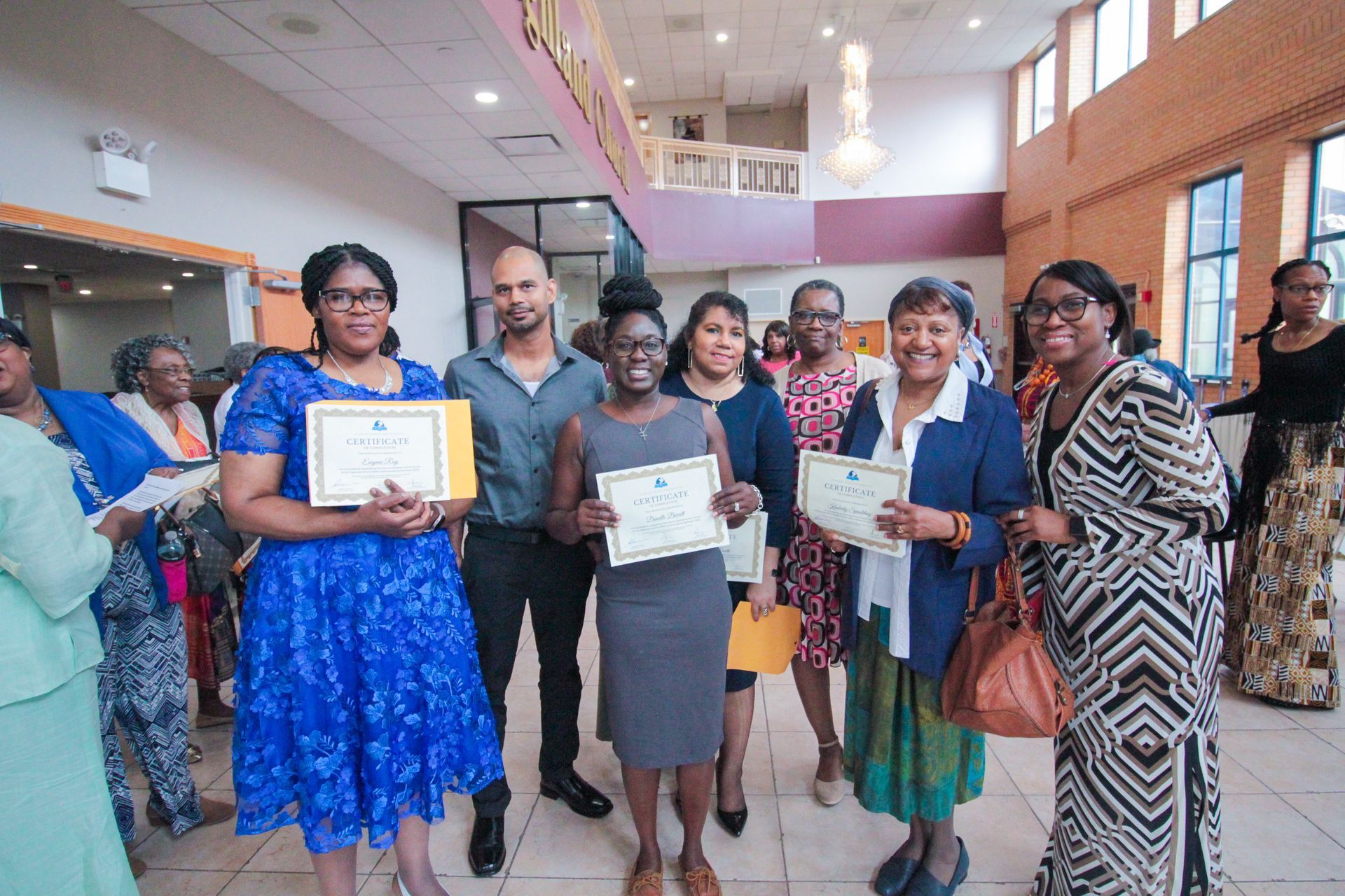A group of people are standing in a room holding certificates.