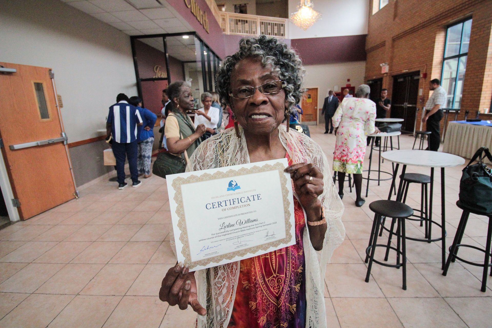 An older woman is holding a certificate in a room.