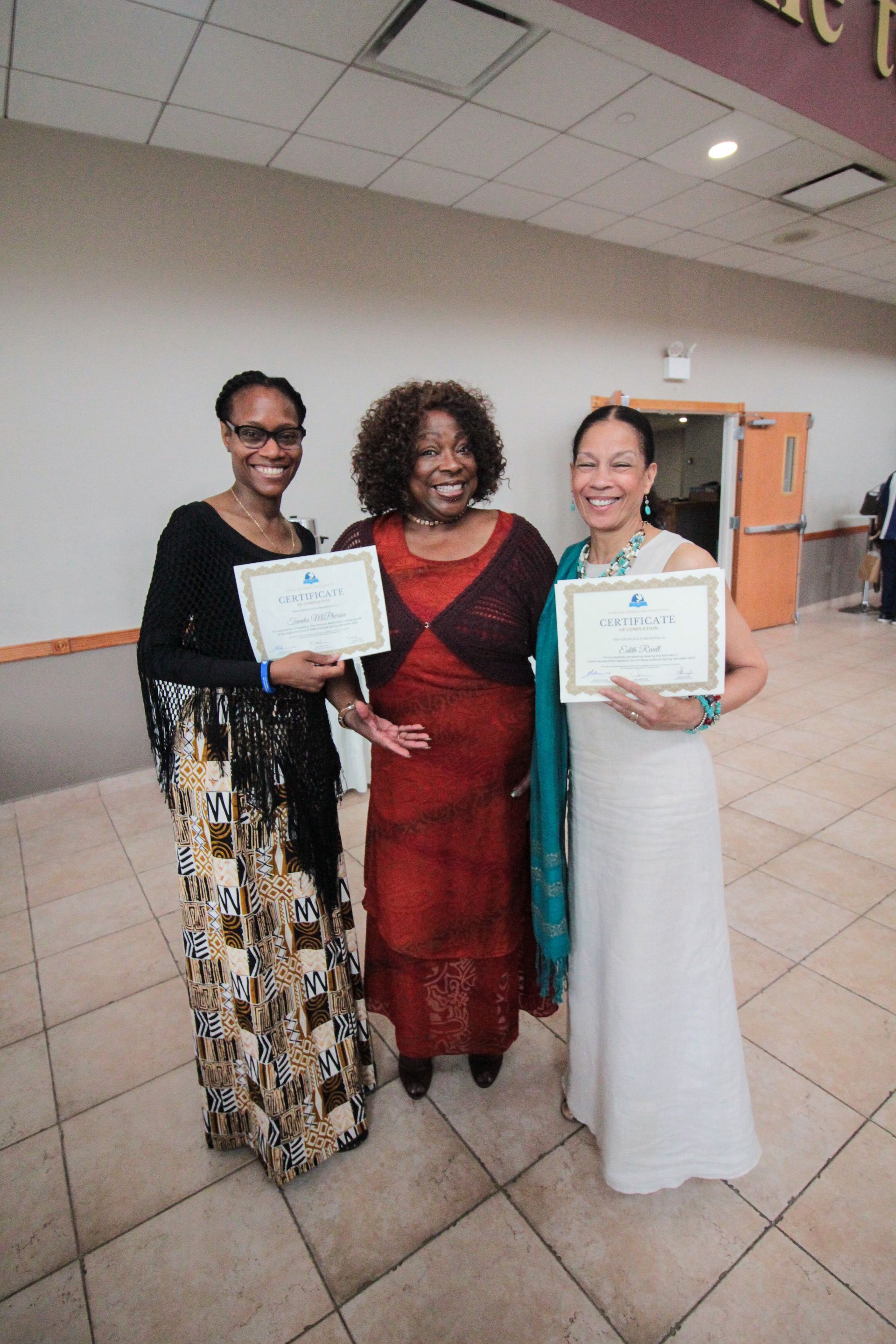 Three women are standing next to each other holding certificates.