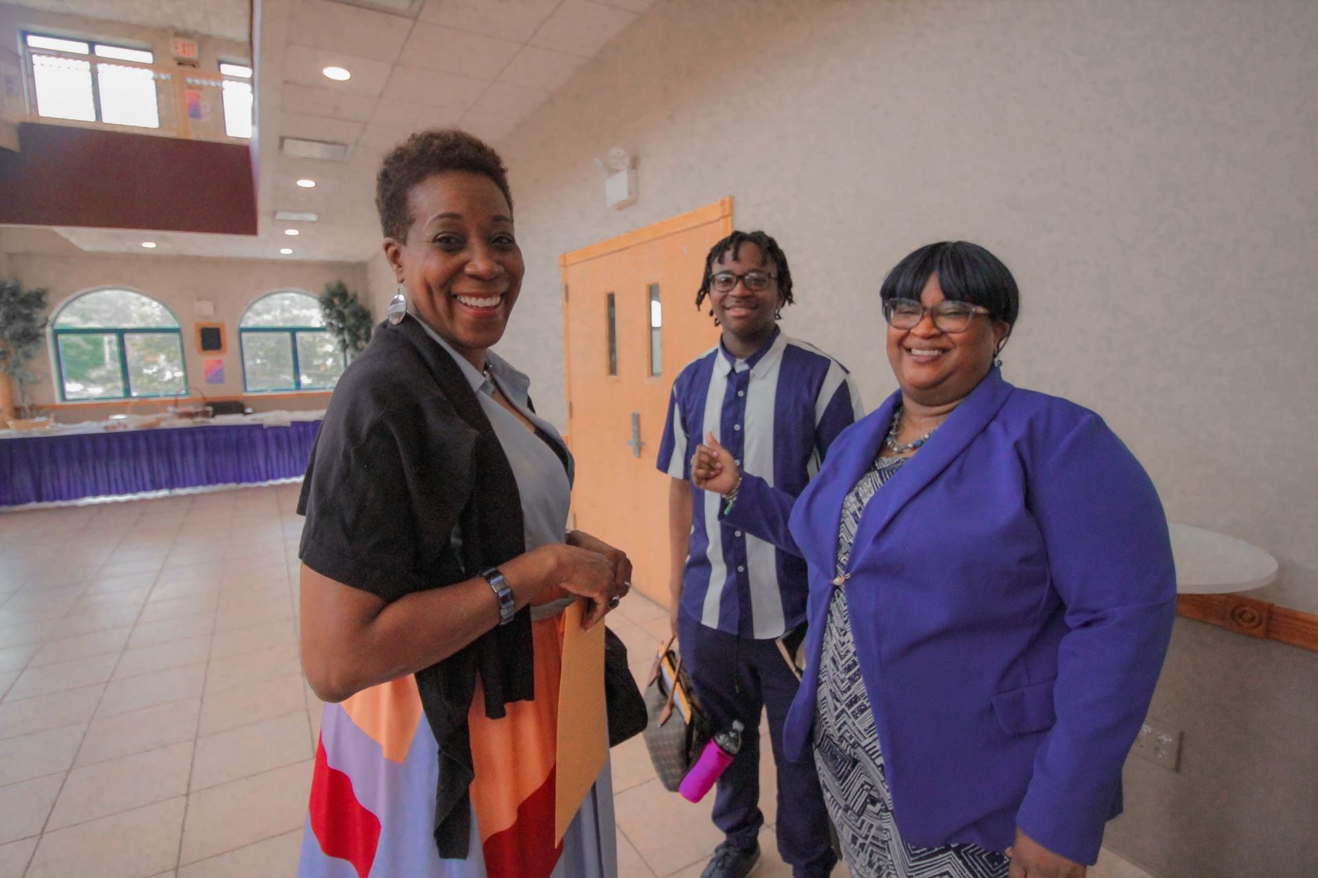 Three people are standing next to each other in a room and smiling.