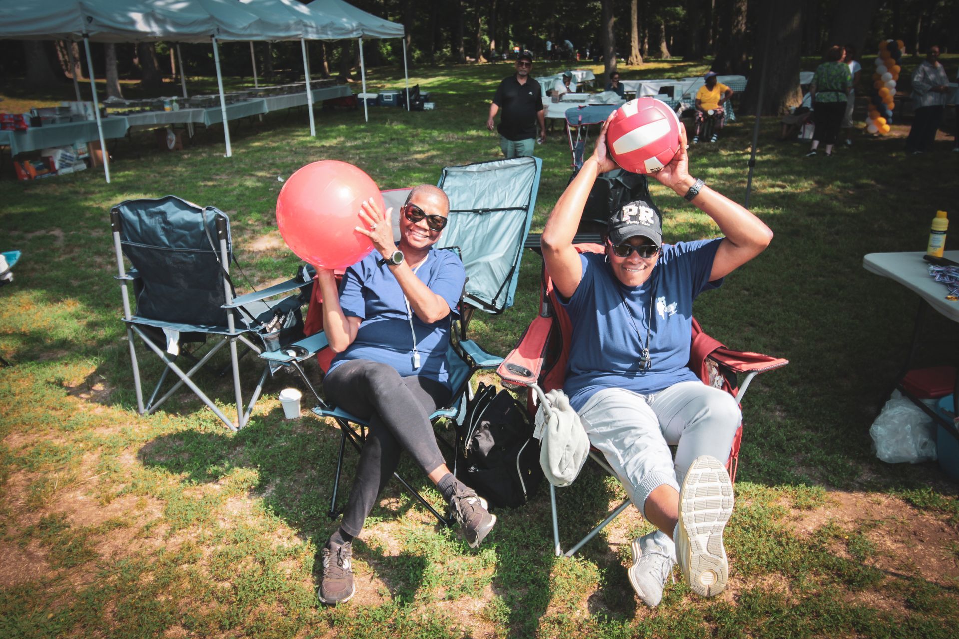 Two women are sitting in chairs holding balloons in their hands.