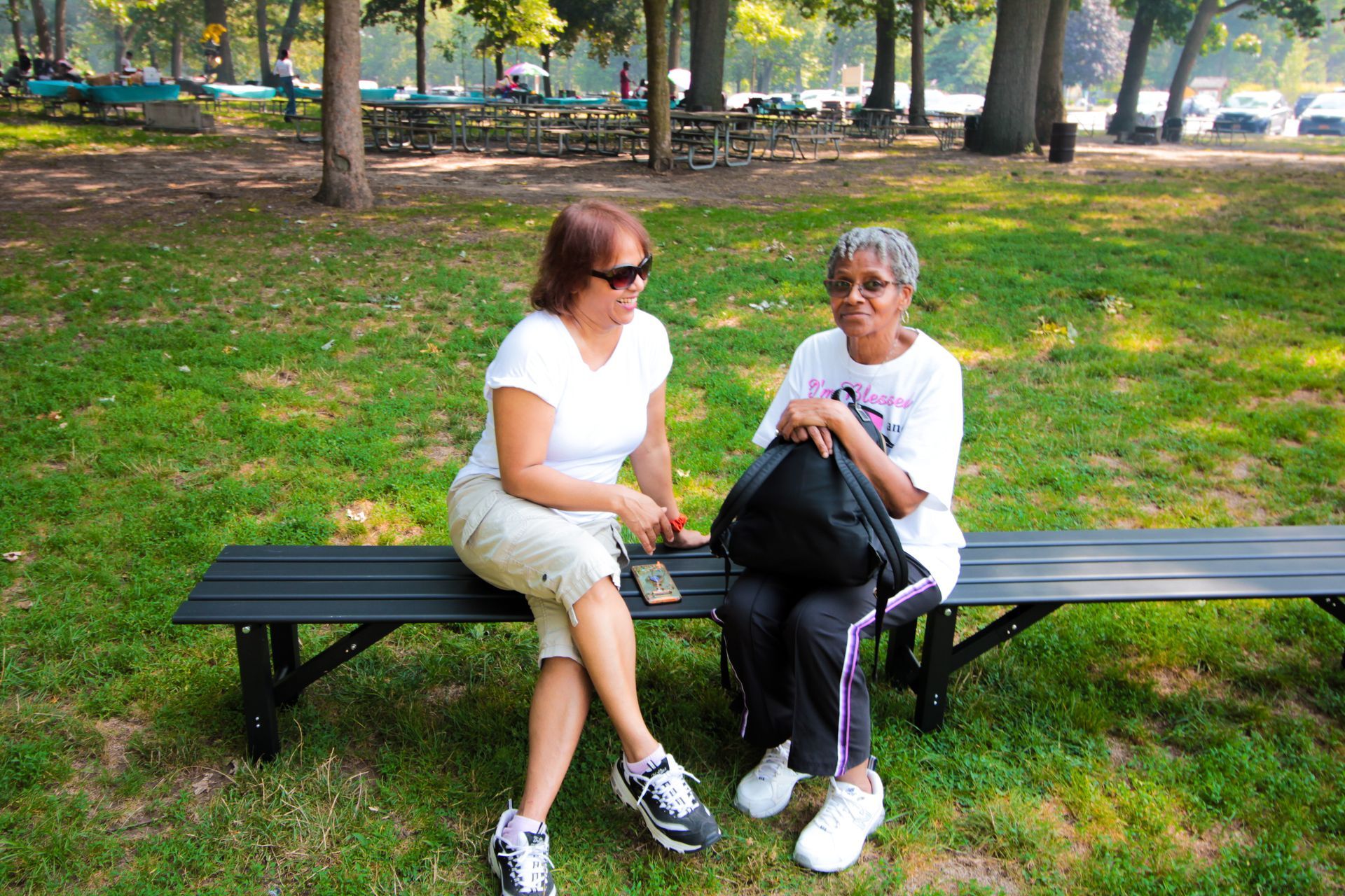 Two women are sitting on a park bench talking to each other