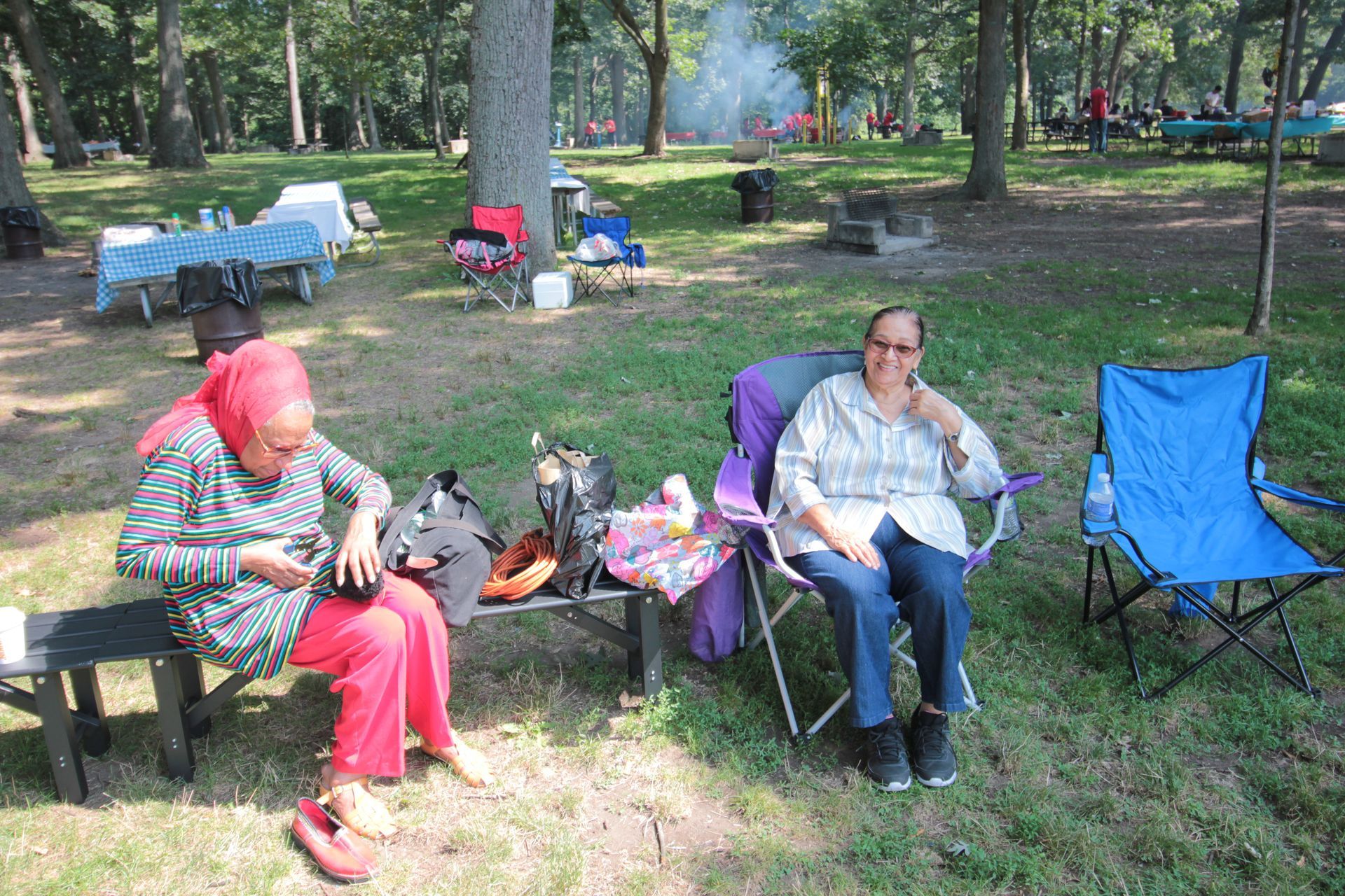 Two women are sitting on a bench in a park.
