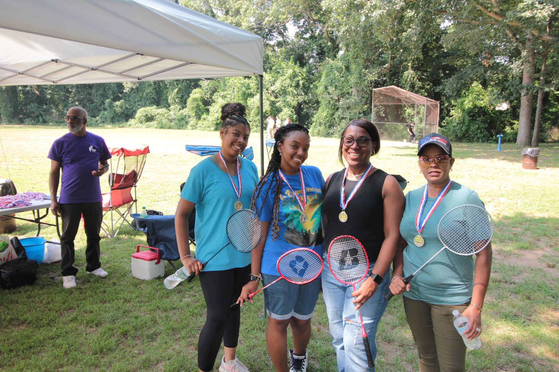 A group of women are posing for a picture while holding badminton rackets.