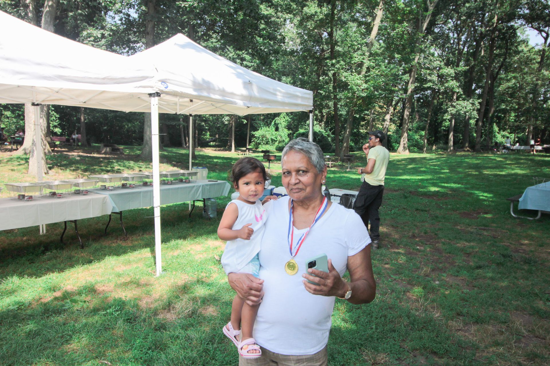 A woman is holding a little girl who is wearing a medal around her neck.