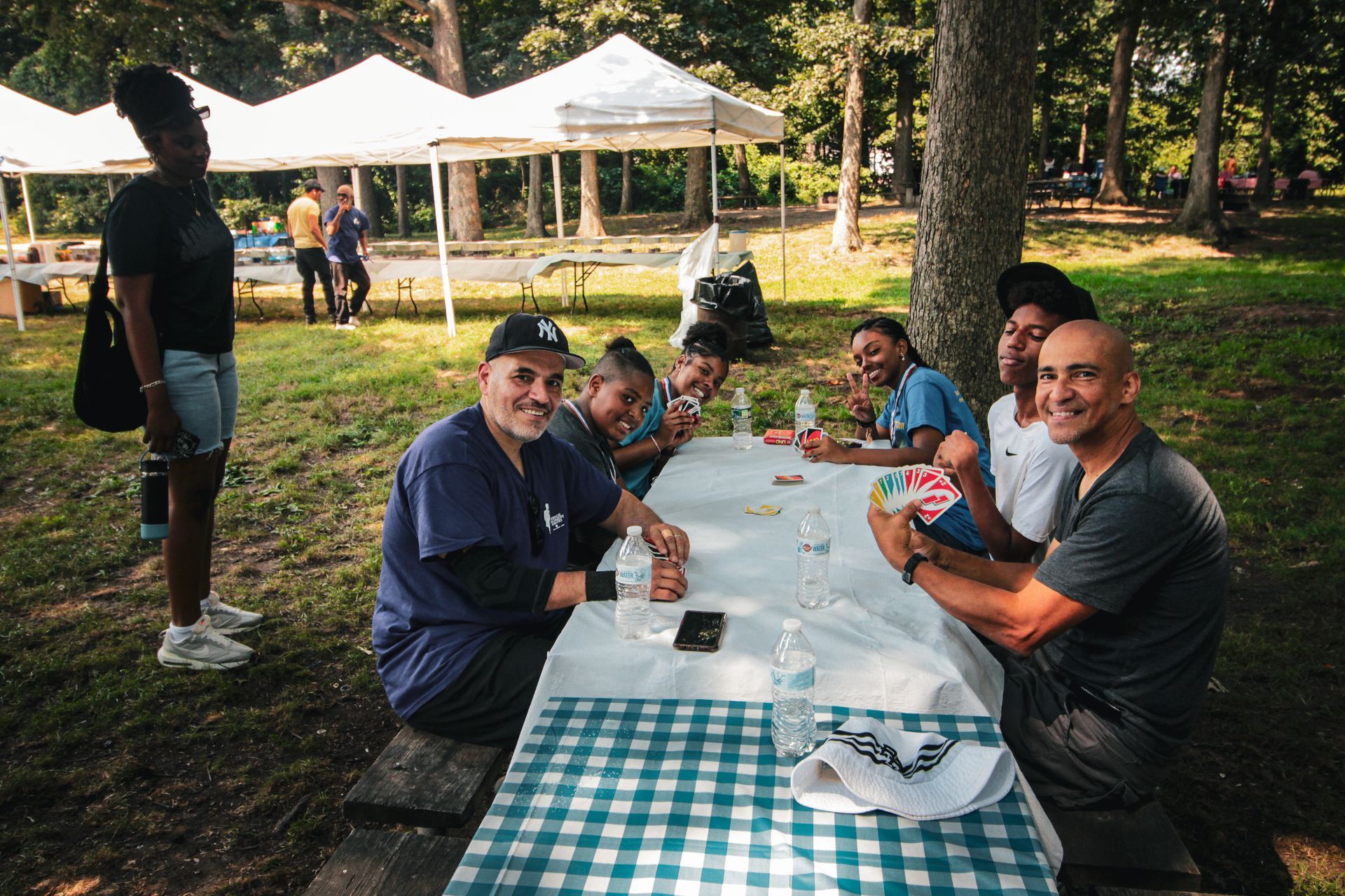 A group of people are sitting at a picnic table in a park.