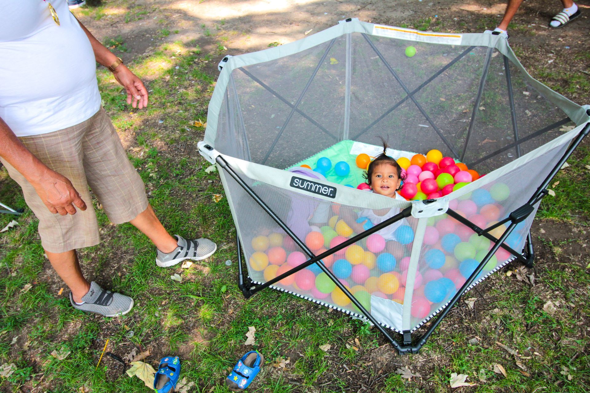 A baby is sitting in a playpen filled with colorful balls.