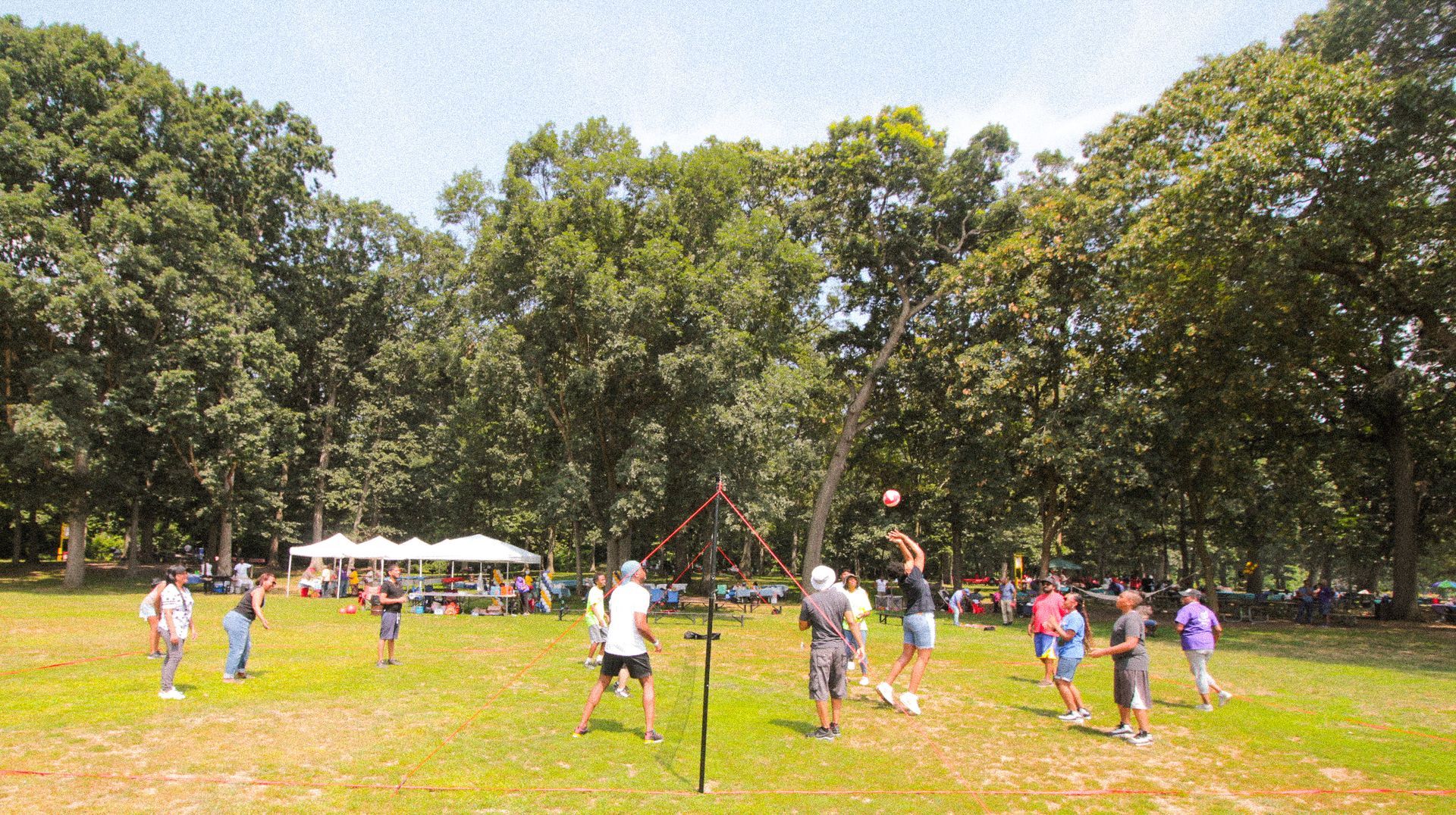 A group of people are playing volleyball in a park