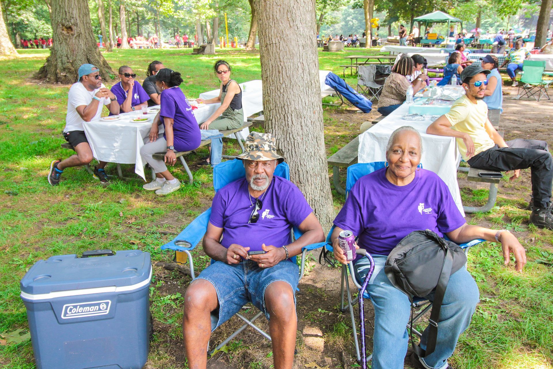 A man and a woman are sitting in chairs in a park.