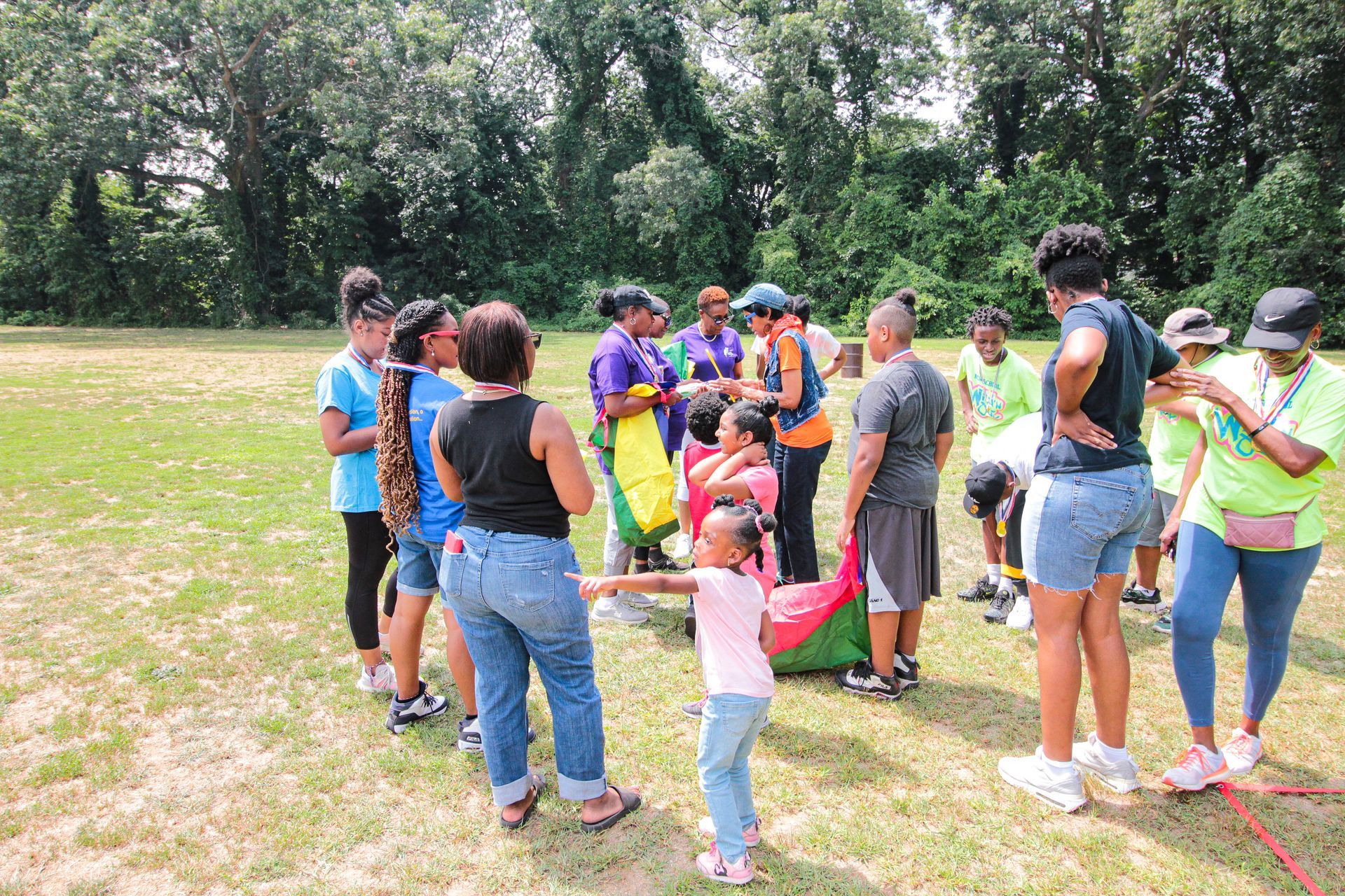 A group of people are standing around a little girl in a field.