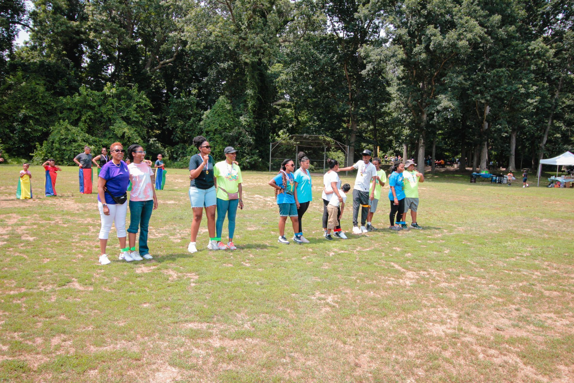 A group of people are standing in a field with trees in the background.