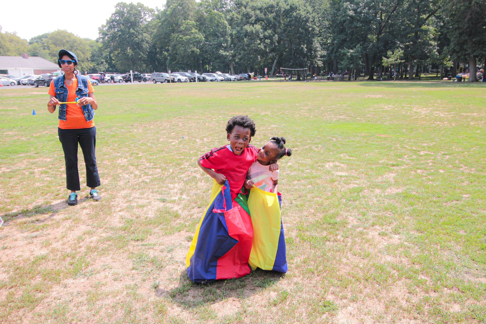 A boy and a girl are playing in a colorful bag in a field.