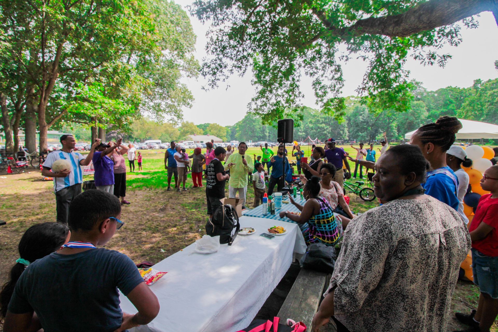 A group of people are standing around a table in a park.