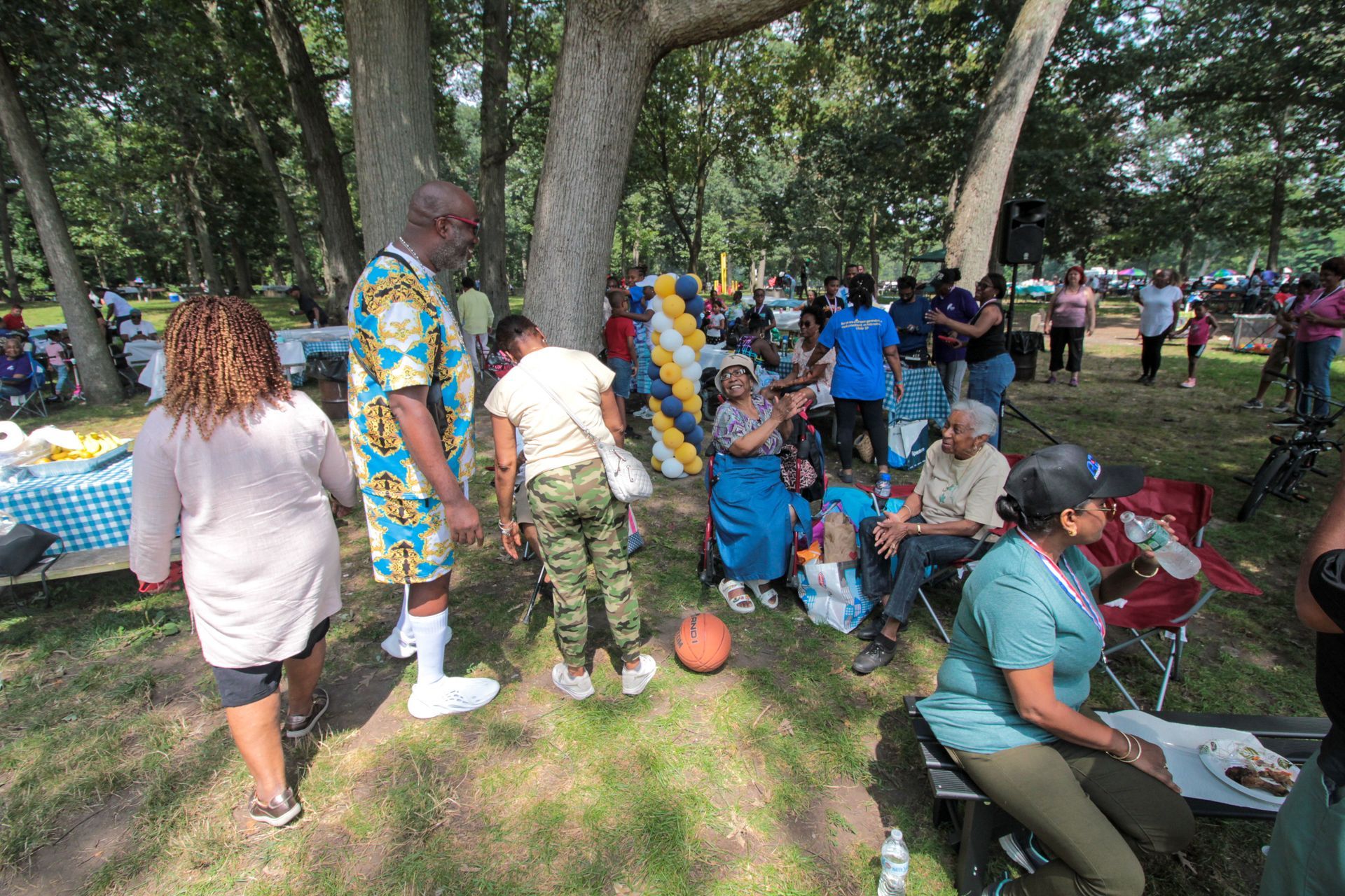 A group of people are standing and sitting in a park.