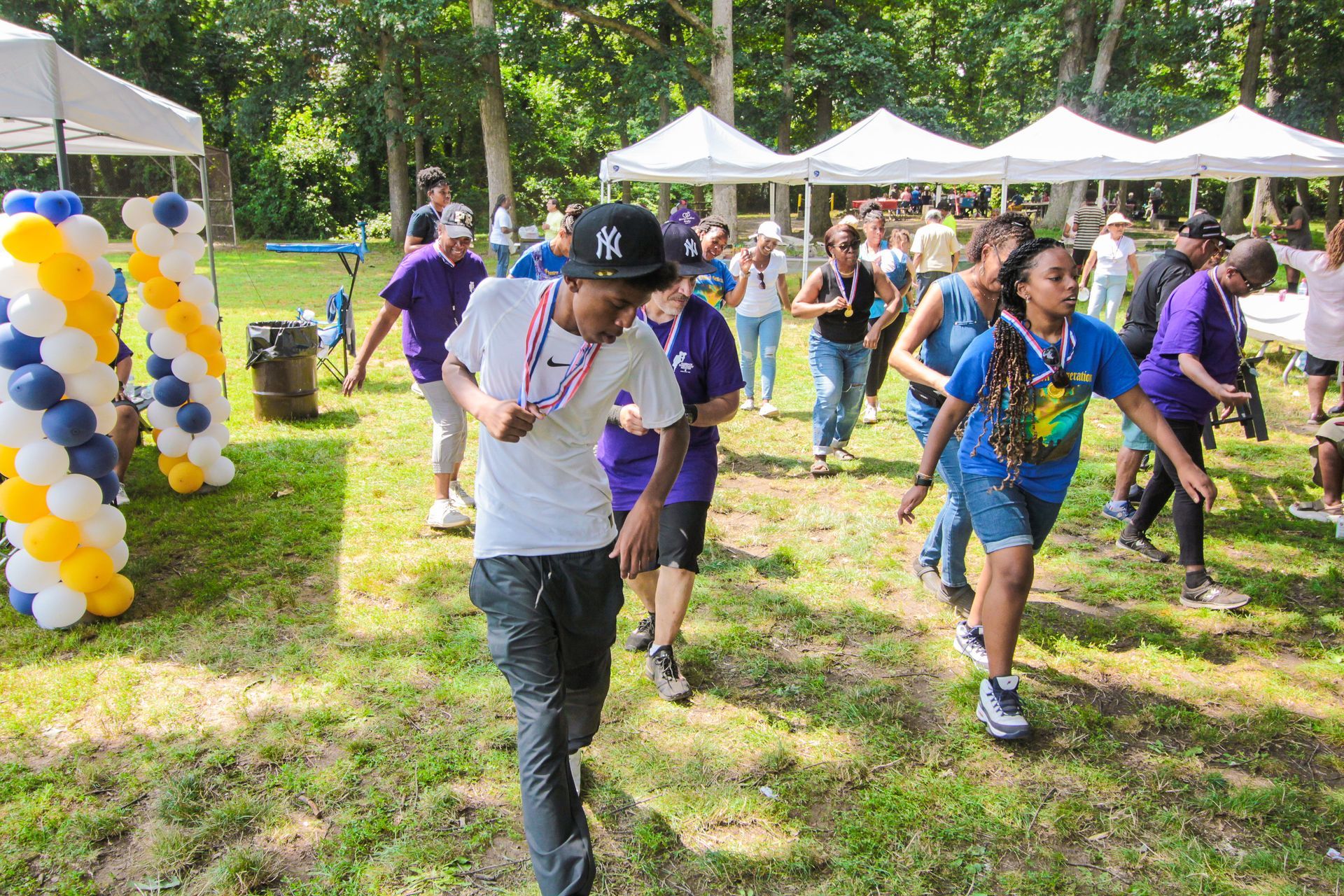 A group of people are running in a park with balloons in the background.