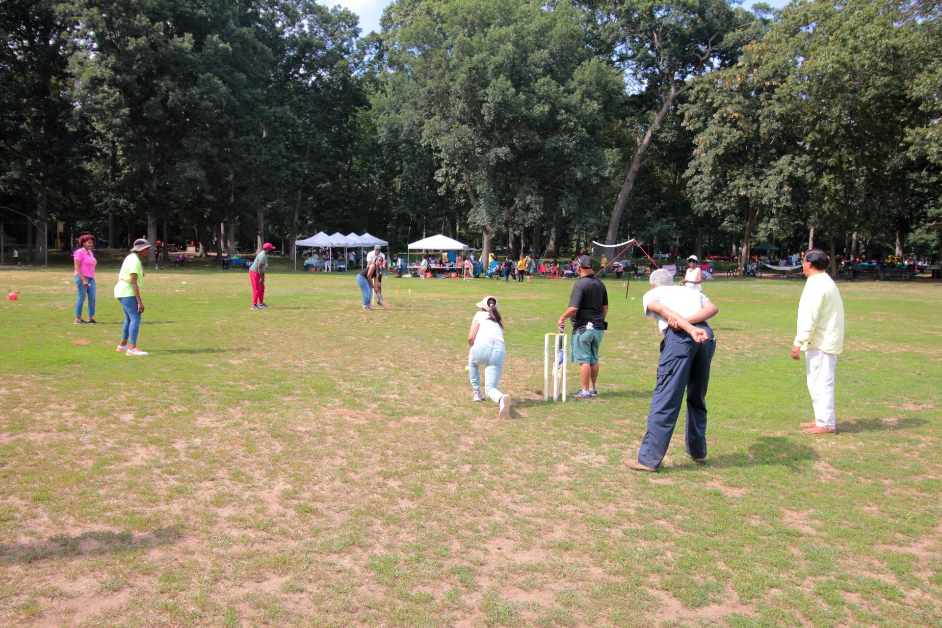 A group of people are playing cricket in a field